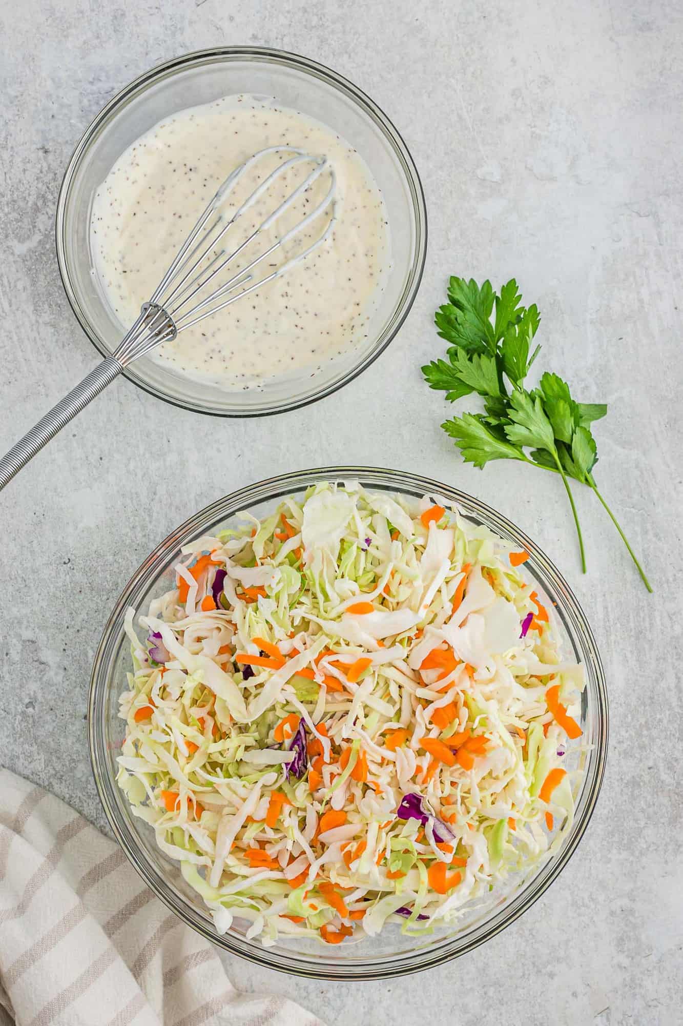 Shredded cabbage in one bowl, coleslaw dressing in another.