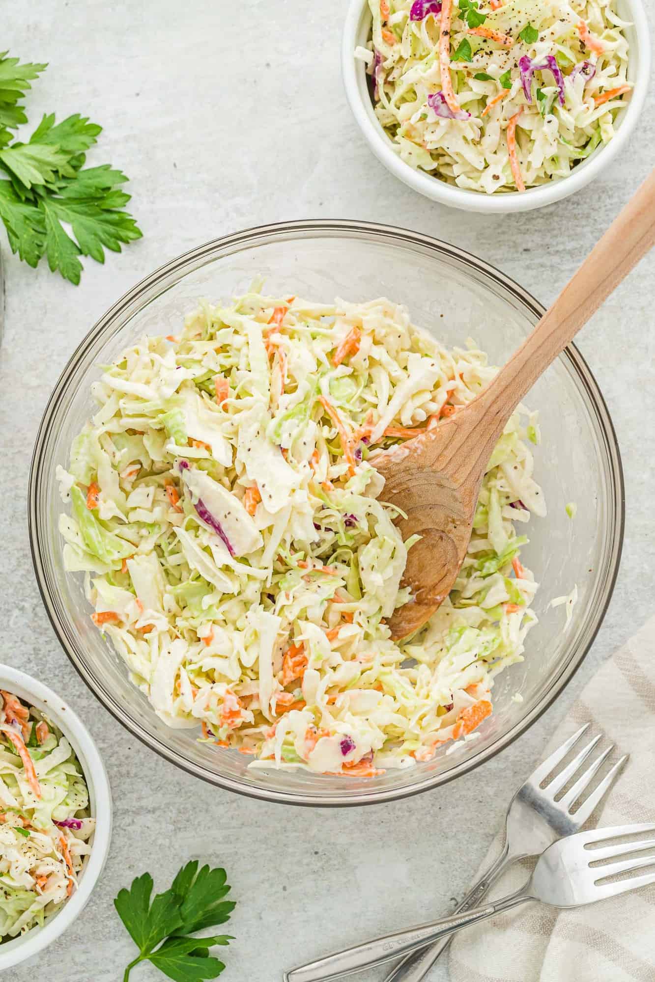 Coleslaw in a large mixing bowl with a wooden spoon.