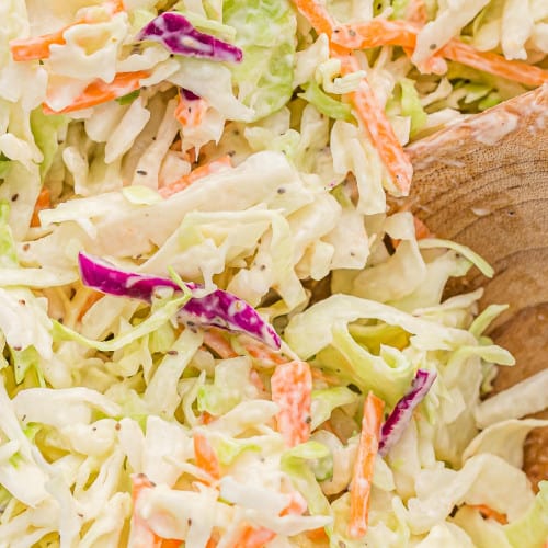 Close up of creamy coleslaw and a wooden spoon.