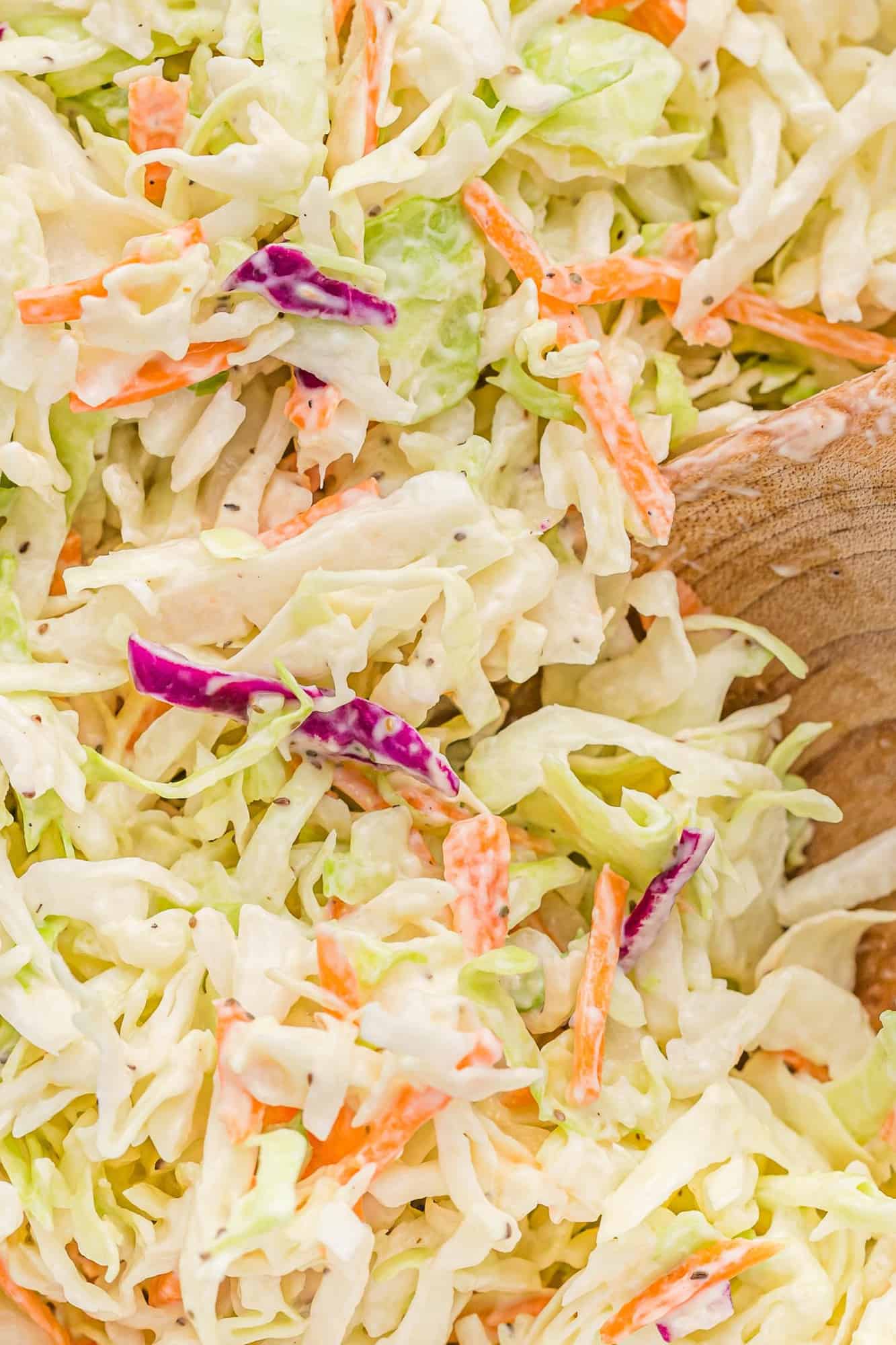 Close up of creamy coleslaw and a wooden spoon.