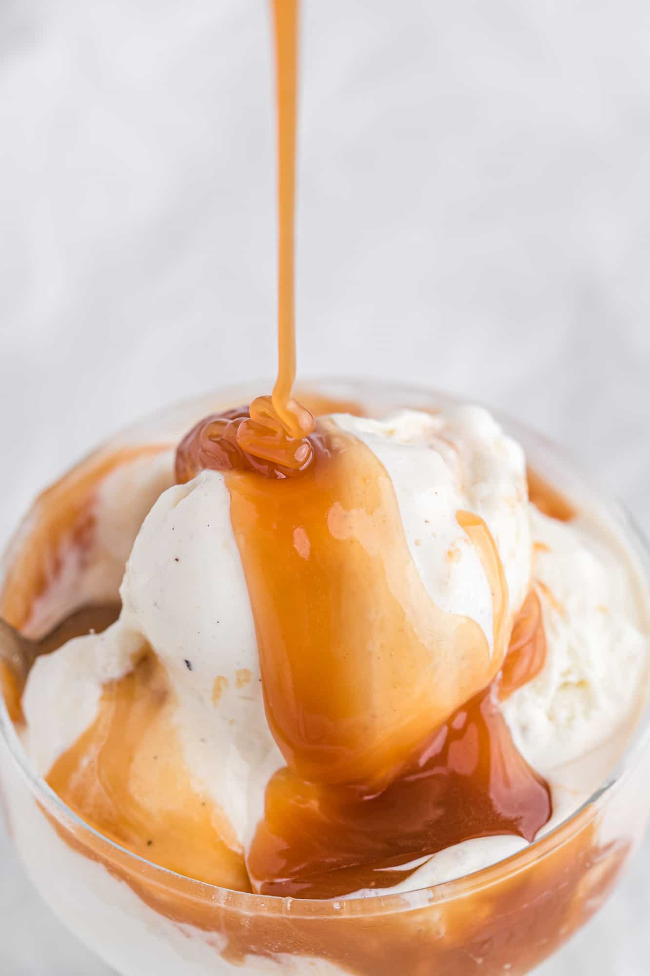 Homemade caramel sauce being poured on ice cream.