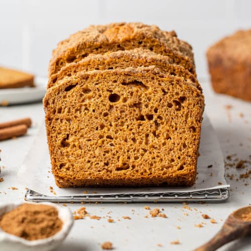 Sliced pumpkin streusel bread with spices around it.