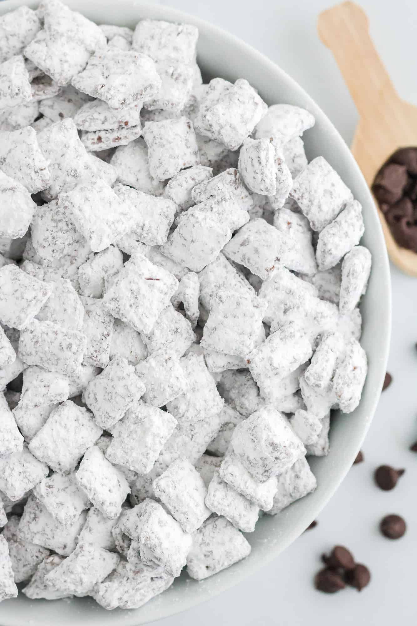 Overhead view of puppy chow in a white bowl, small chocolate chips visible as well.