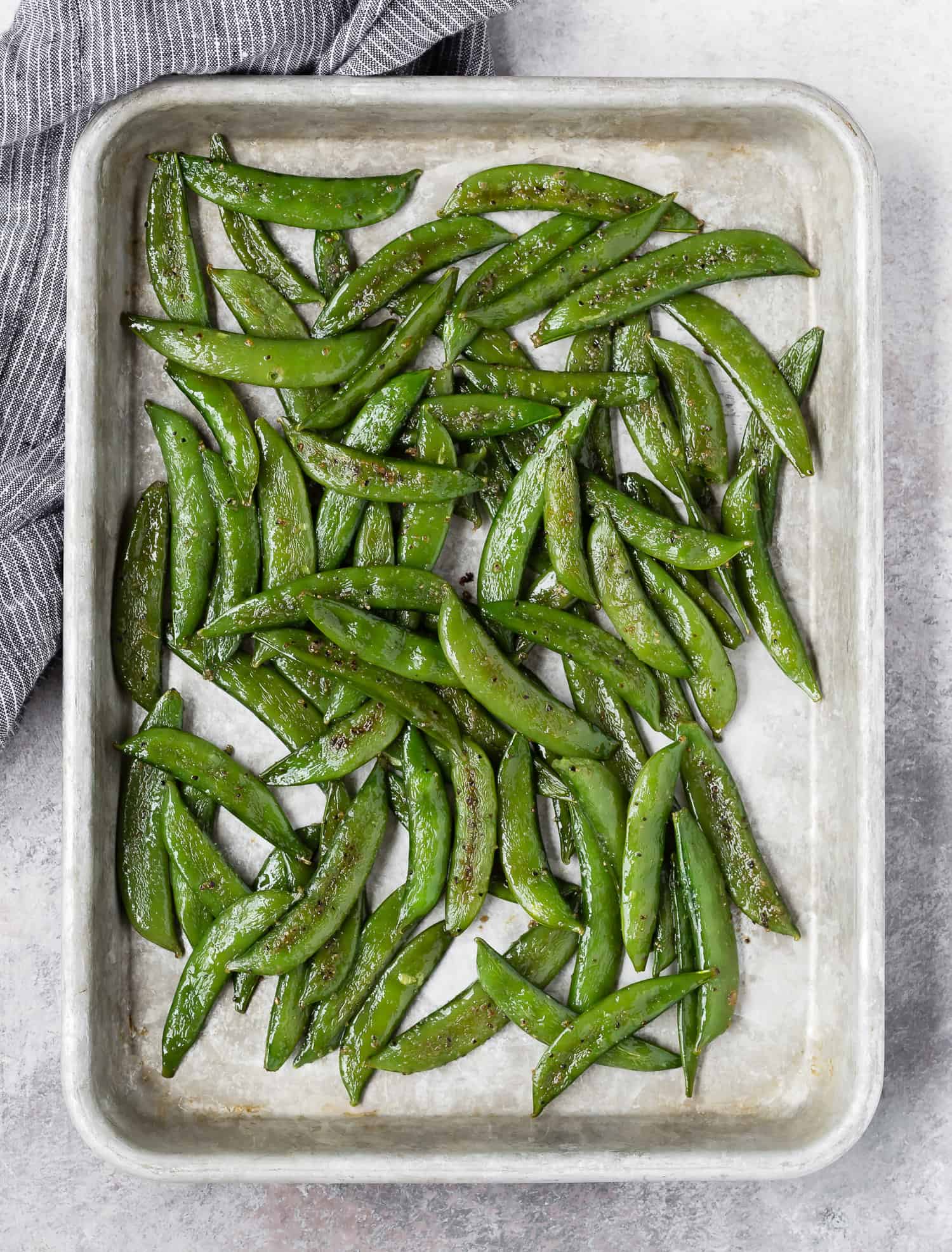 Overhead view of sheet pan with roasted sugar snap peas on it.