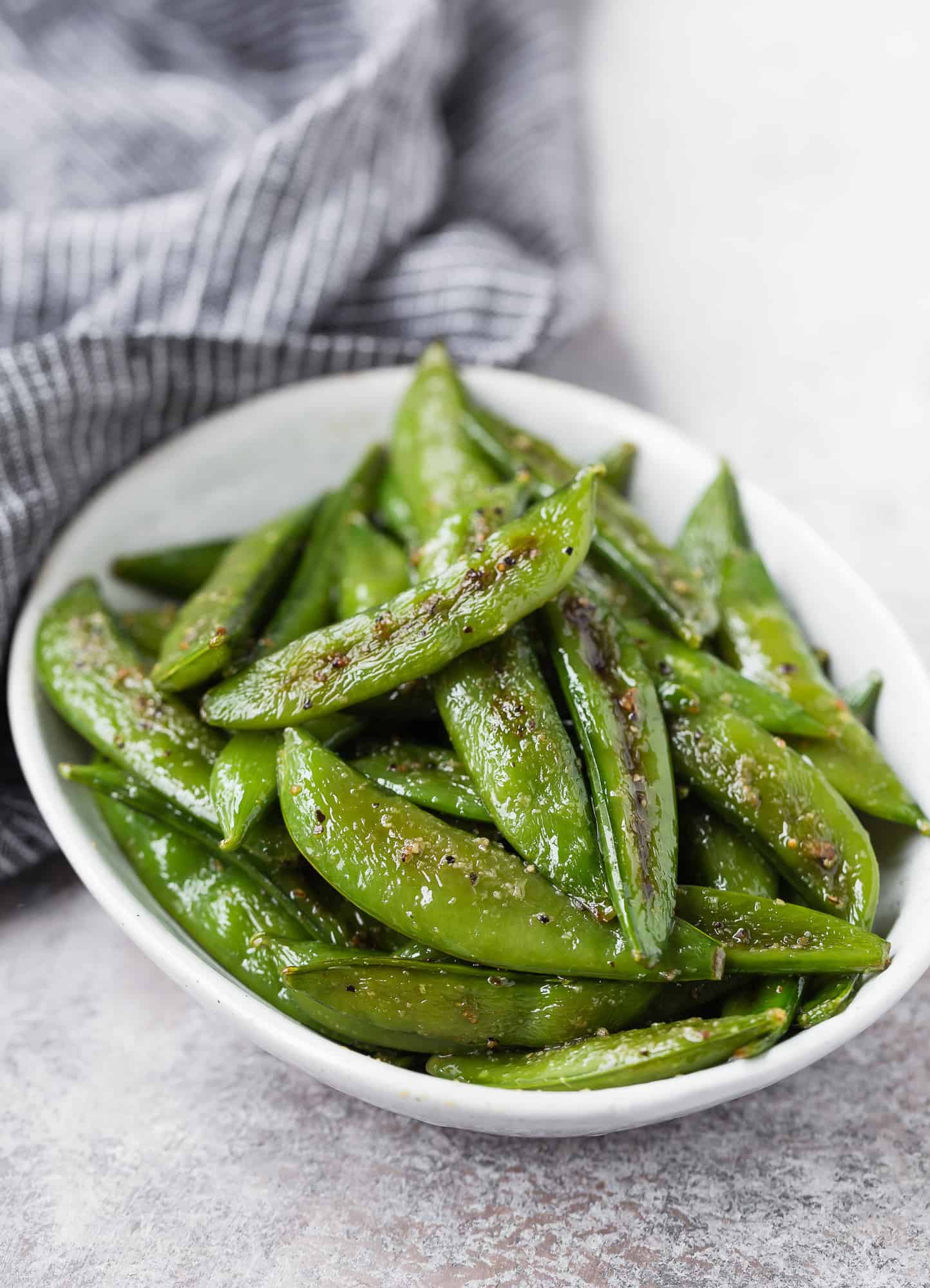 Snap peas in a small white oval bowl.