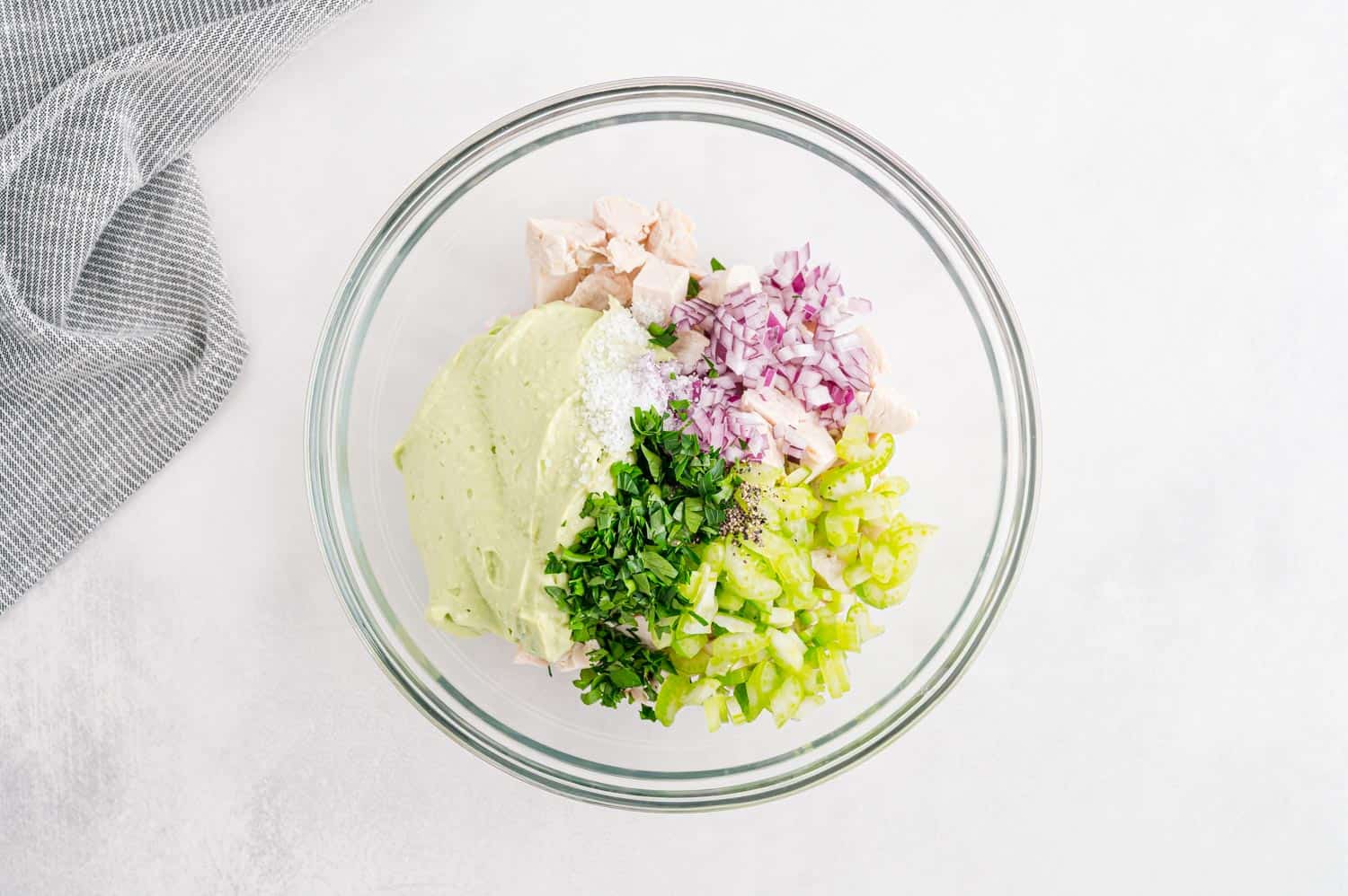 Unmixed chicken salad in clear glass bowl.