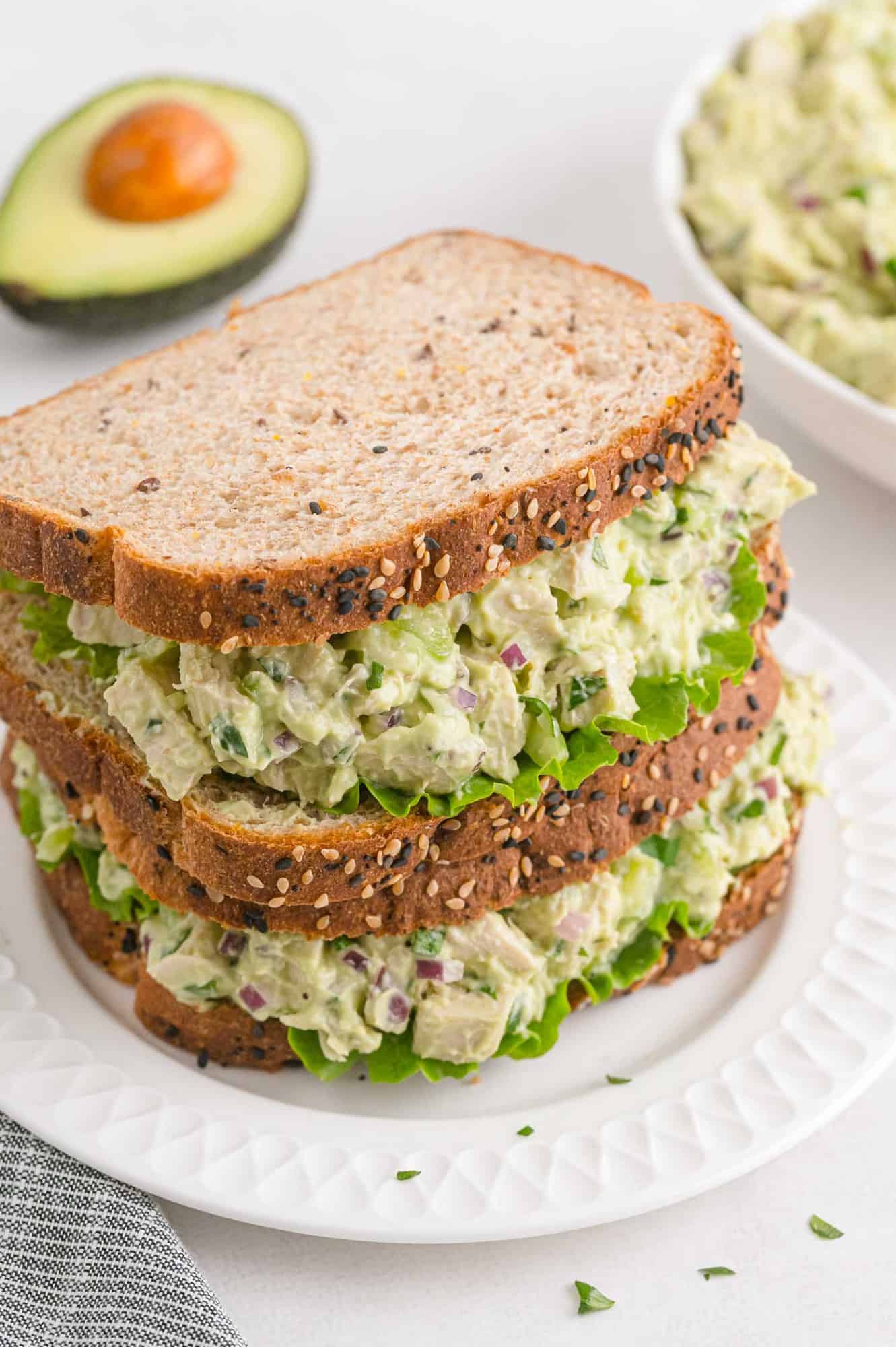 Double stack of avocado chicken salad sandwiches on wheat bread.