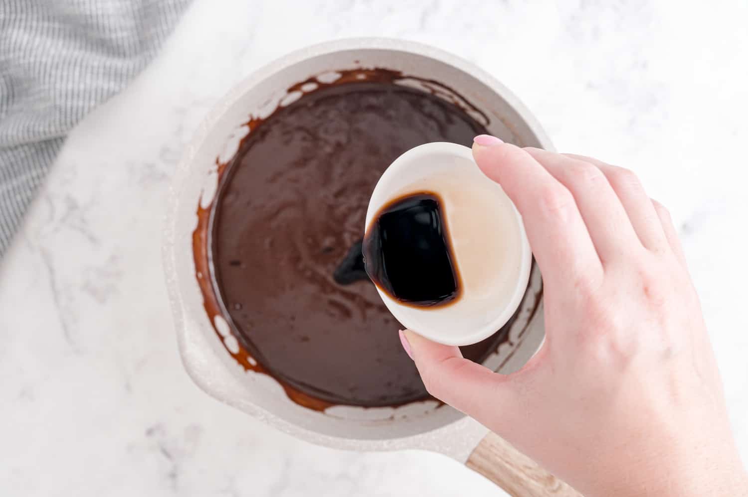 Vanilla being poured into hot fudge.