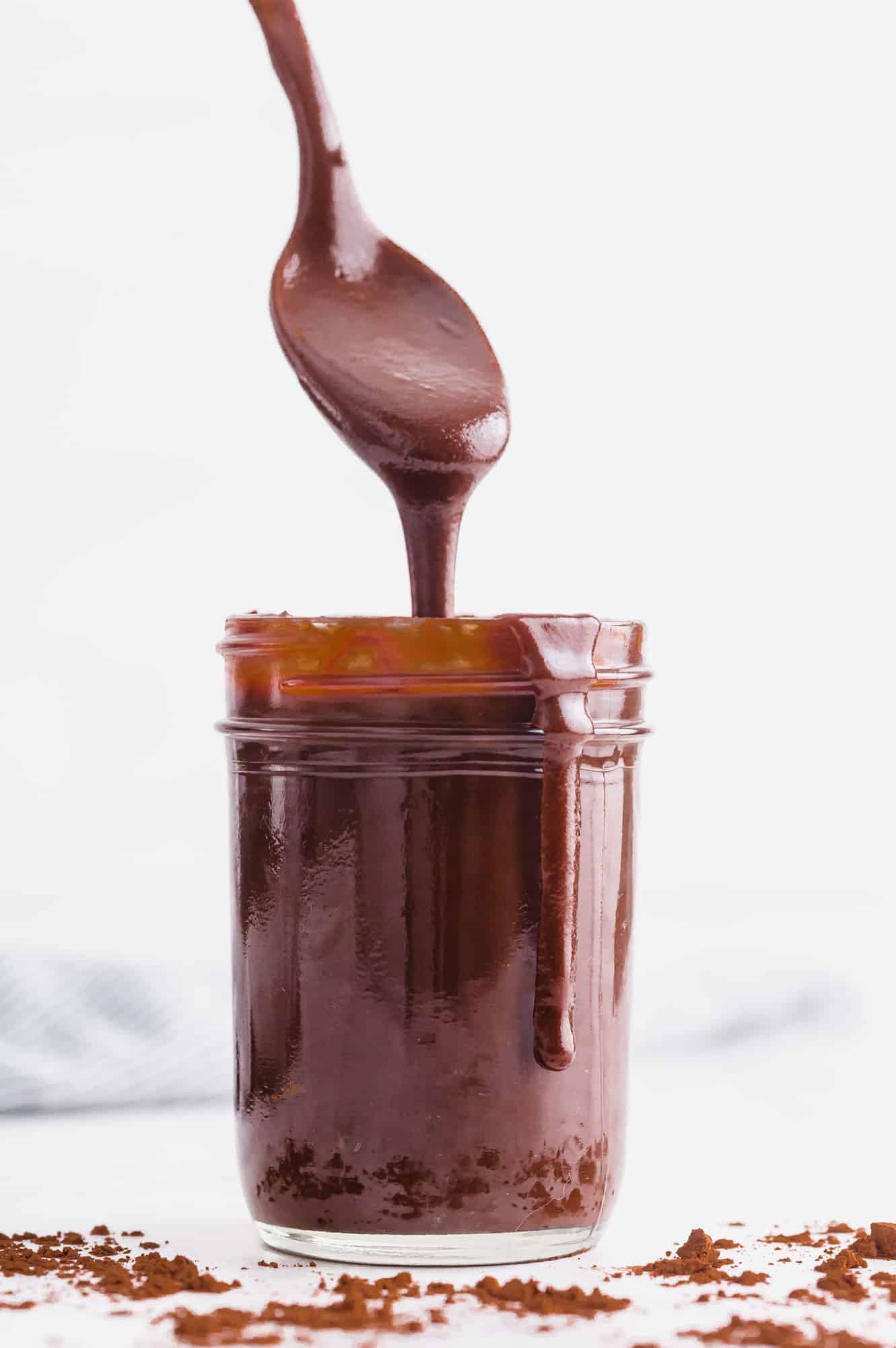 Hot fudge in a messy jar, a spoon coming out jar.
