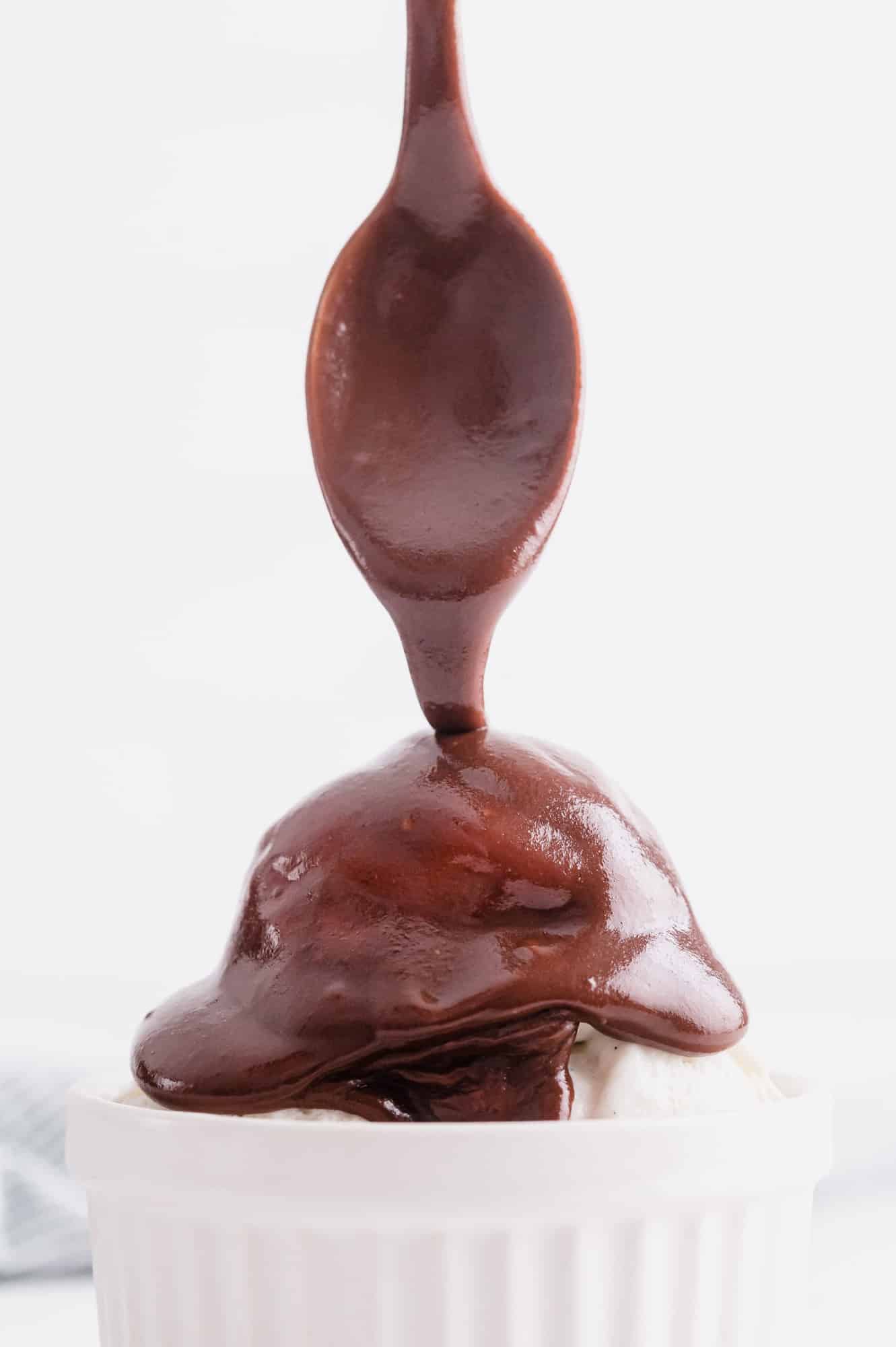 Chocolate sauce being poured on ice cream.