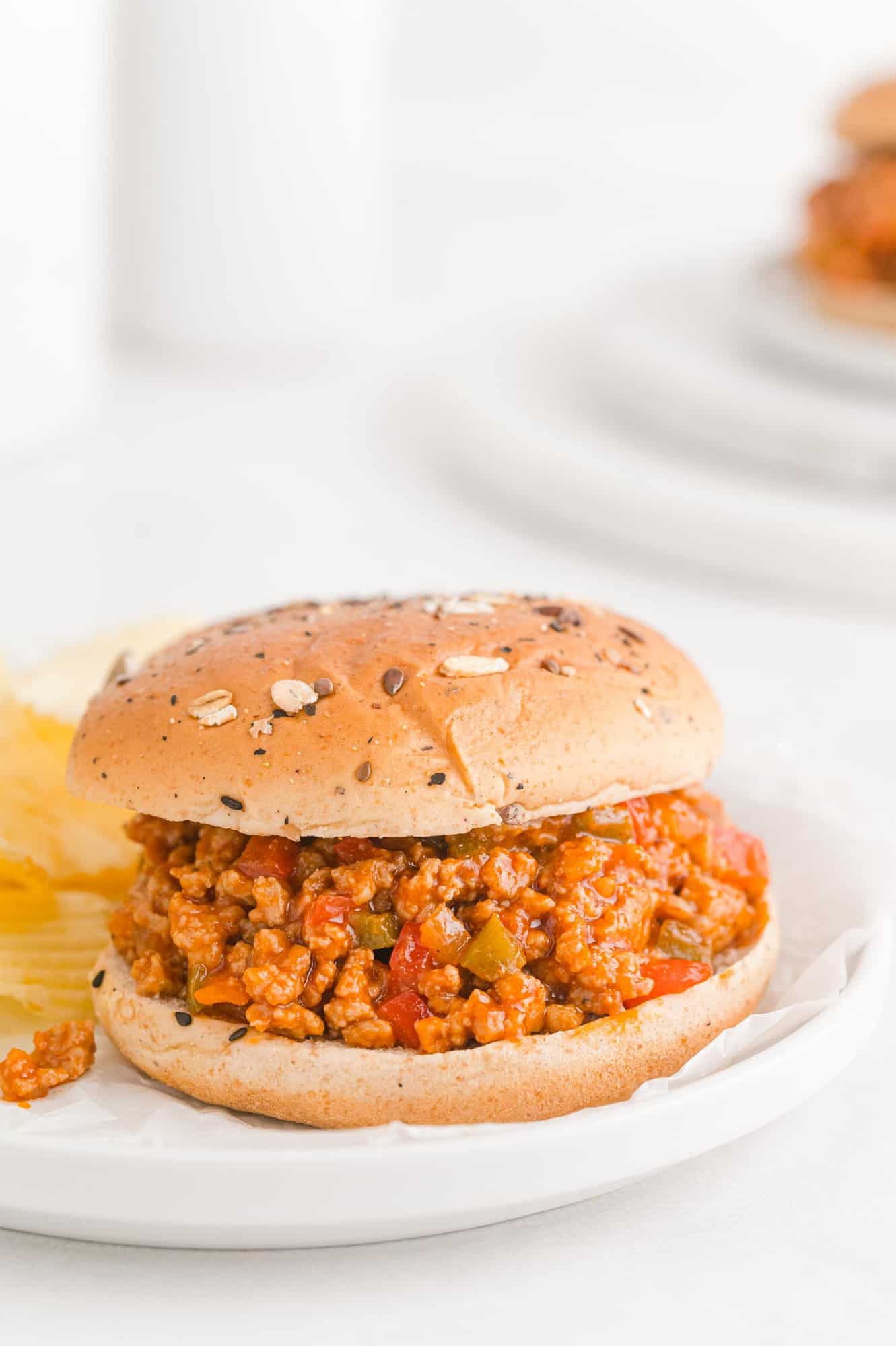 Sandwich with sloppy joe filling on a white plate.