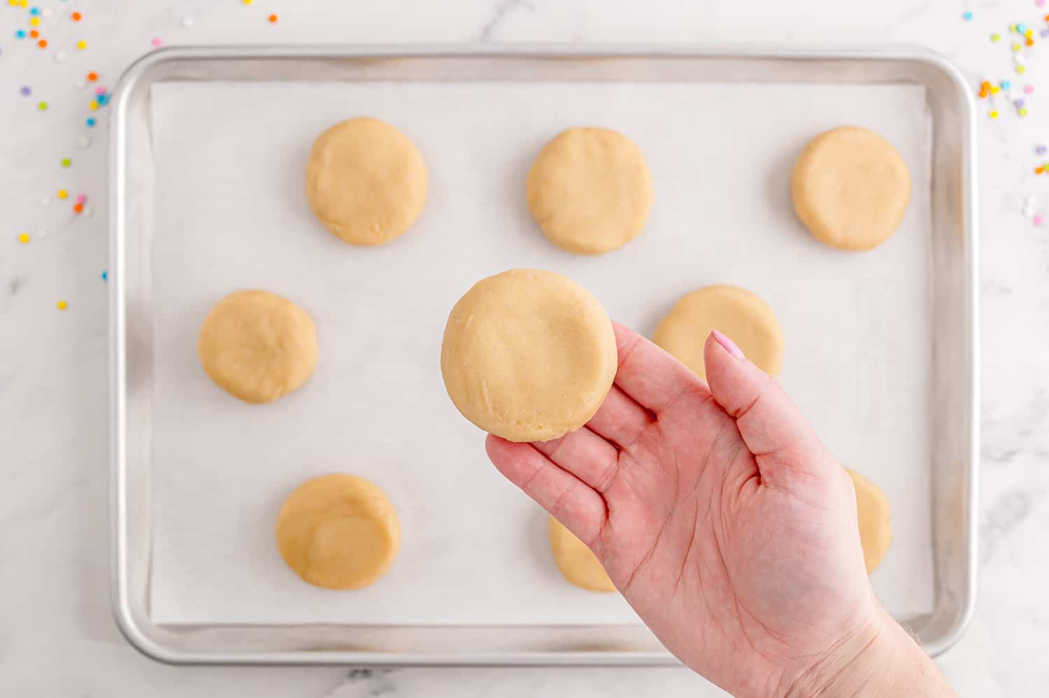 Flattened unbaked cookie in a hand.