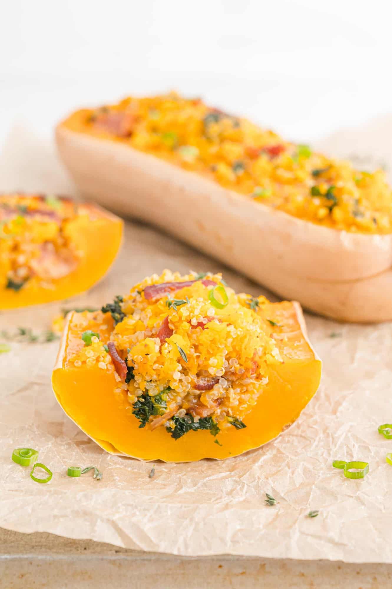 Stuffed butternut squash cut to show filling of quinoa, bacon, kale.