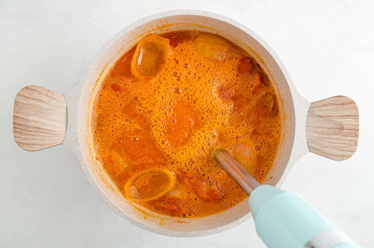 Soup being pureed with an immersion blender.