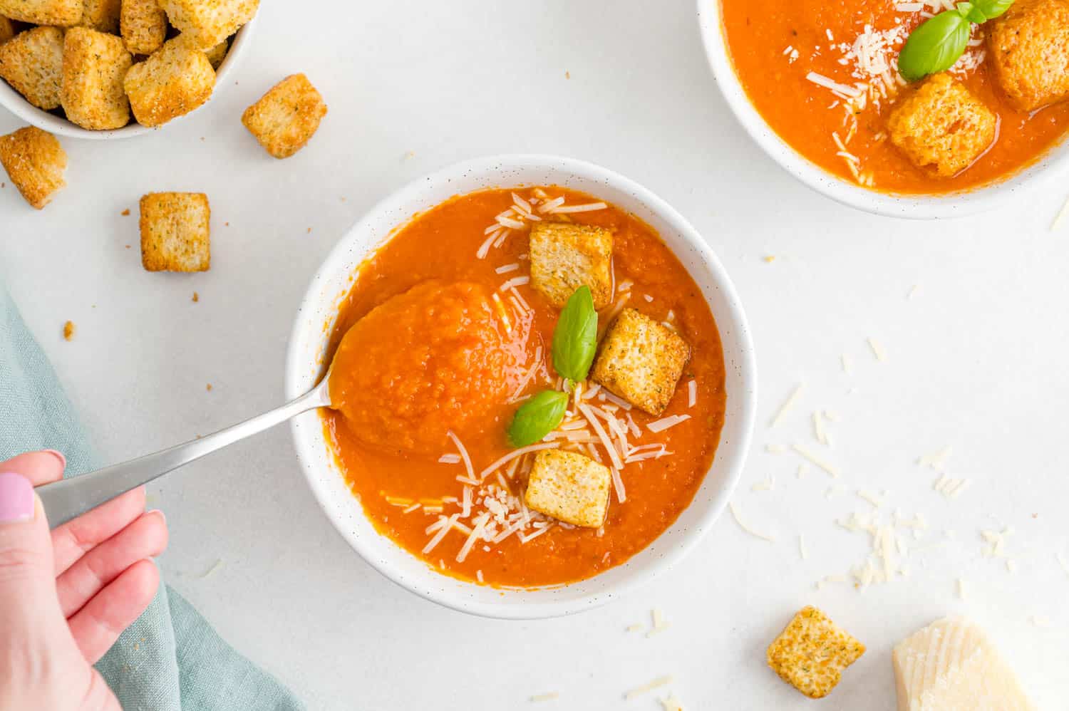 Spoon of tomato soup held in a hand.