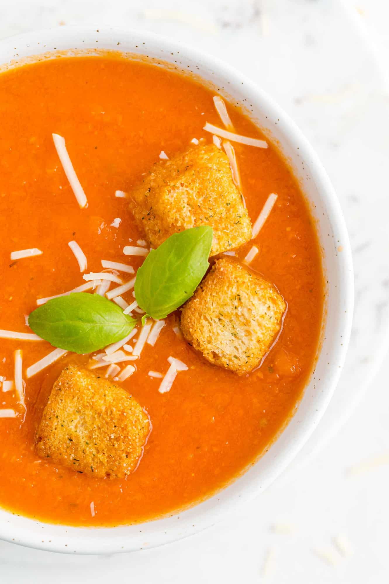 Close up of soup and garnishes in a round white bowl.