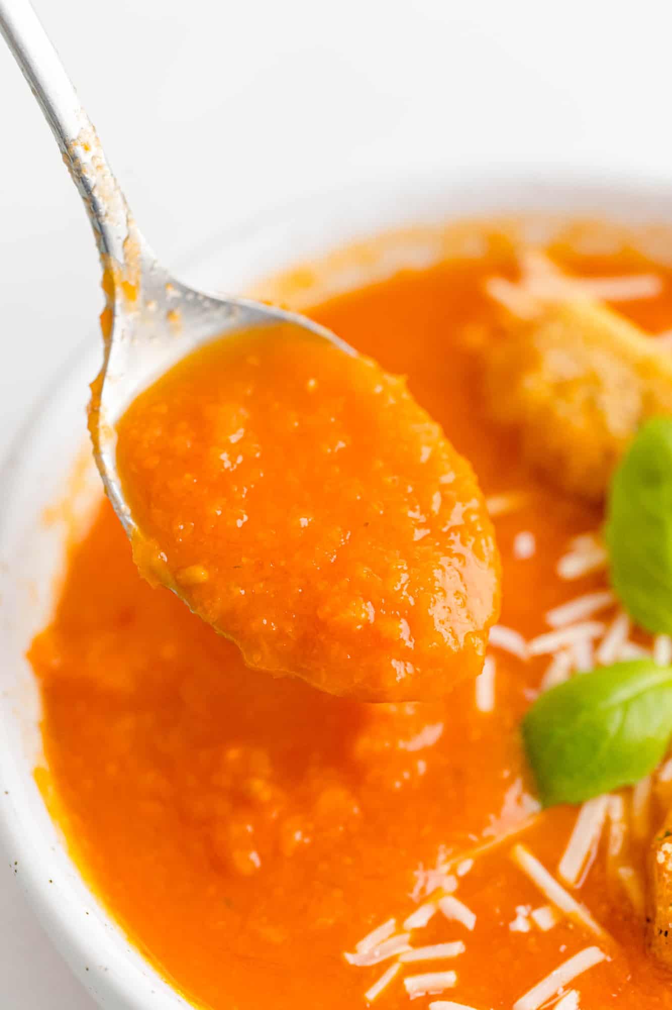 Close up view of tomato soup on a spoon.