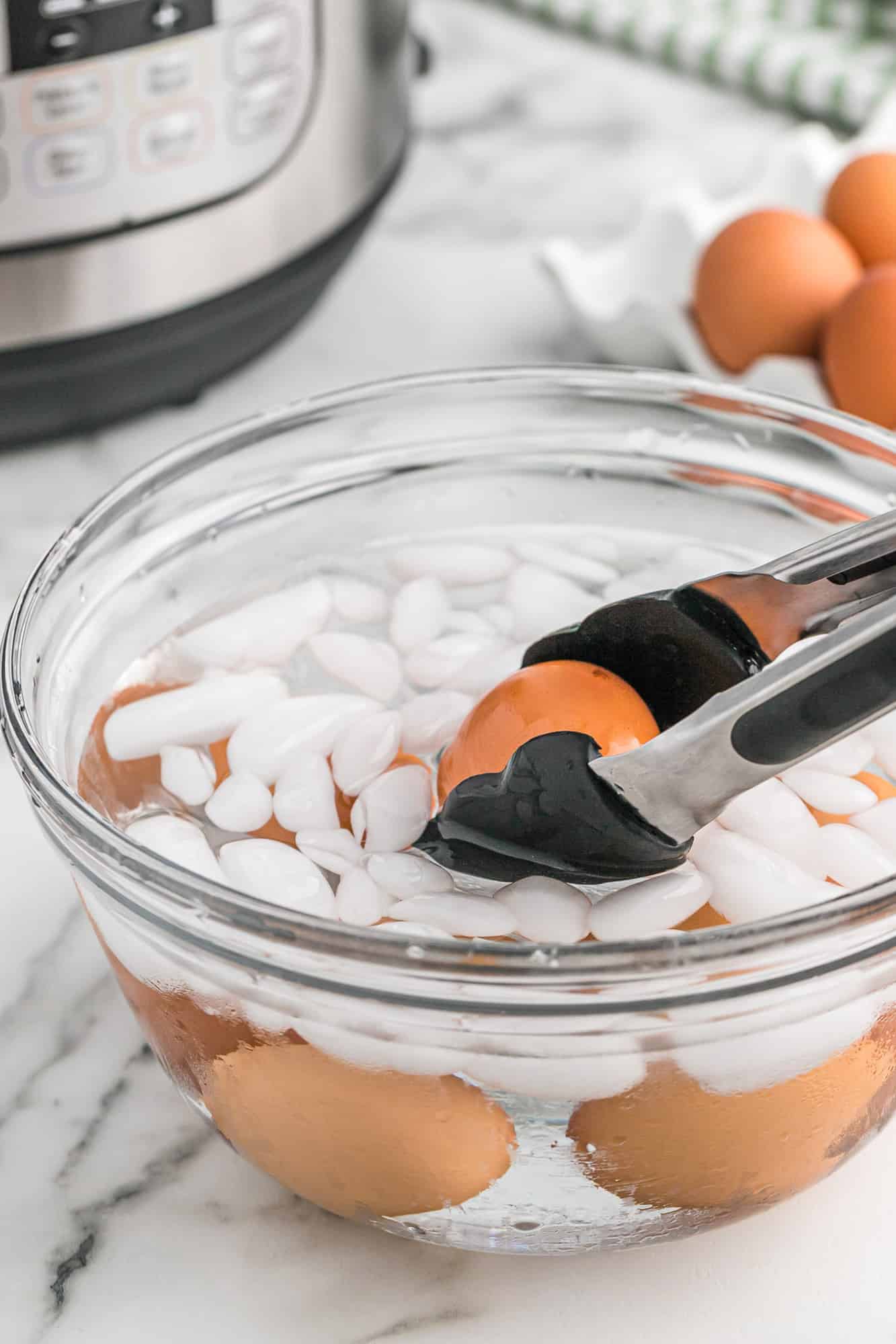 Brown egg being placed in an ice water bath.