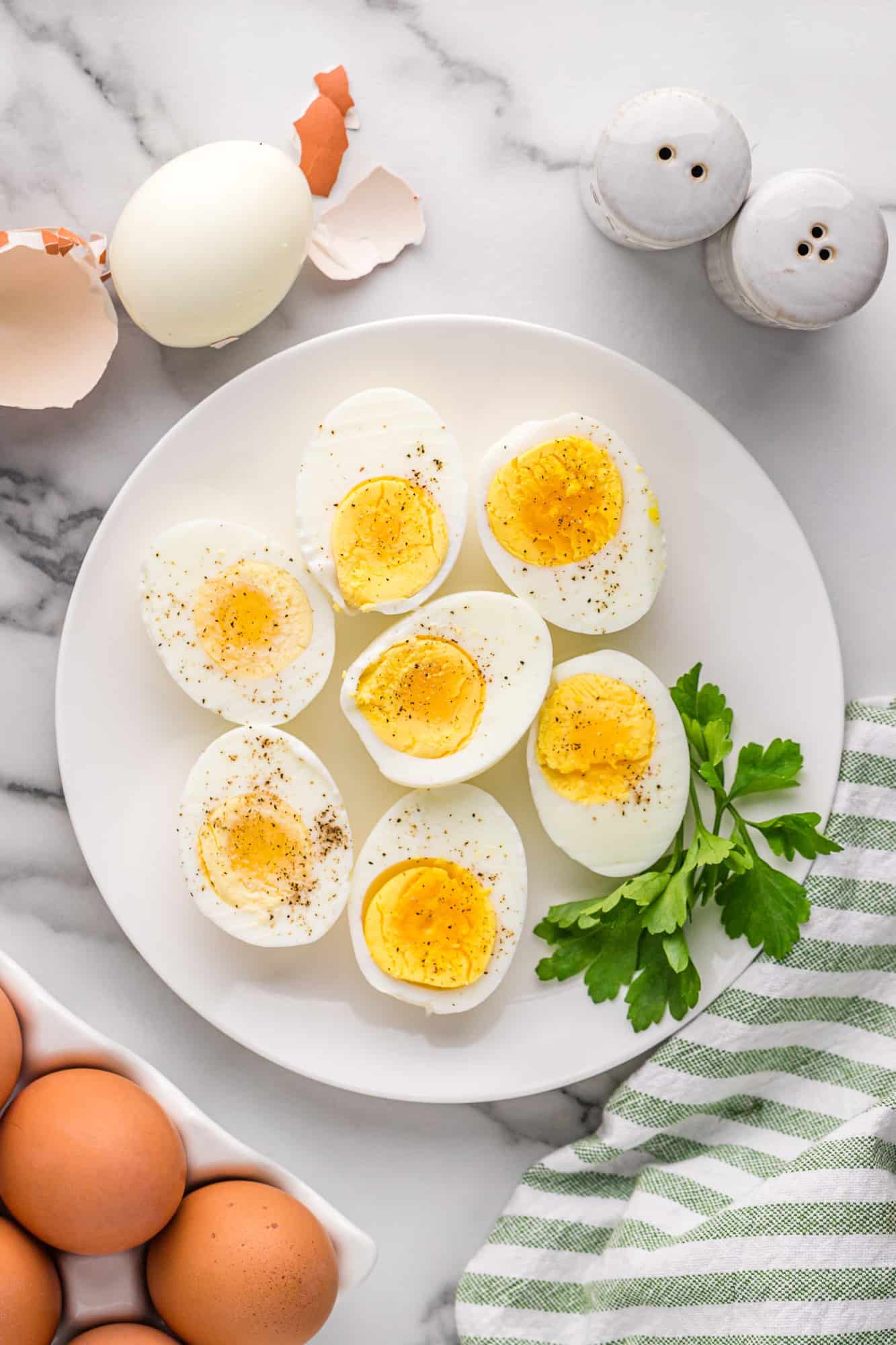 White plate filled with Instant Pot boiled eggs sprinkled with pepper.