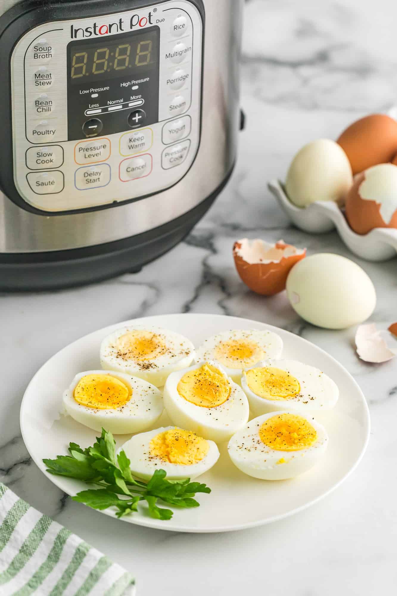 Boiled eggs on a plate in front of an instant pot pressure cooker.