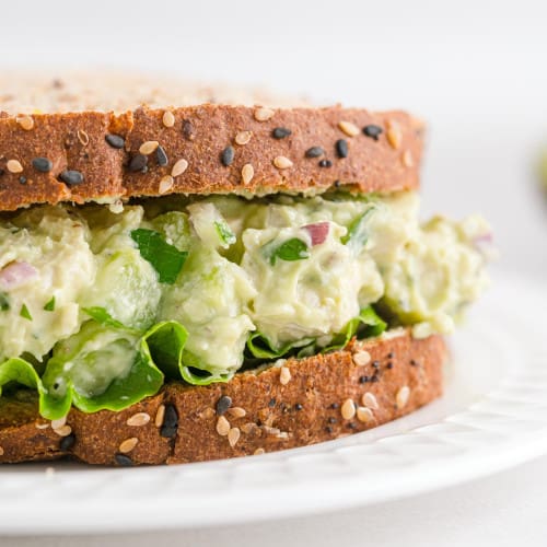 Avocado chicken salad between two slices of multigrain bread.