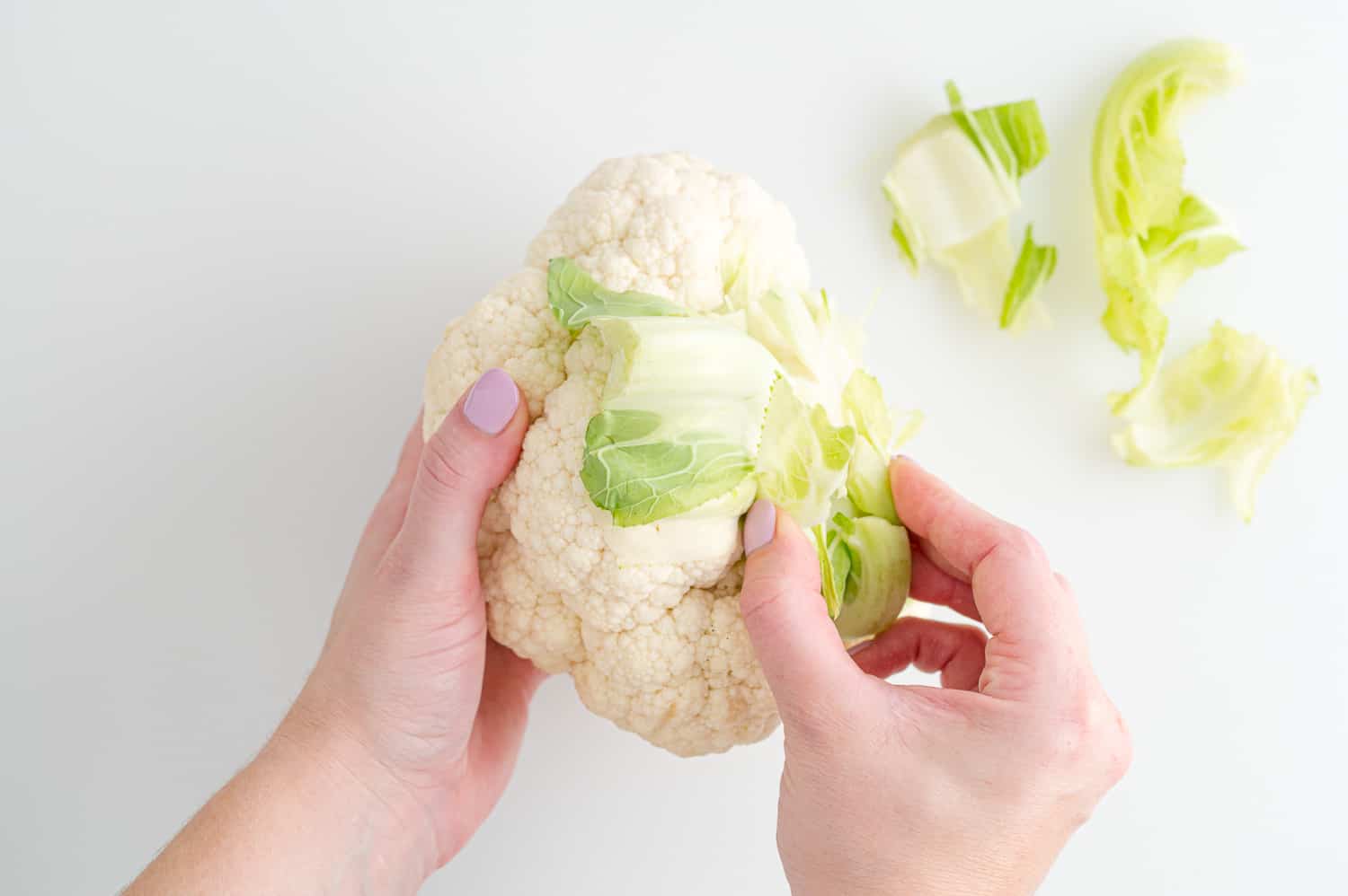 Leaves being removed from a head of cauliflower.