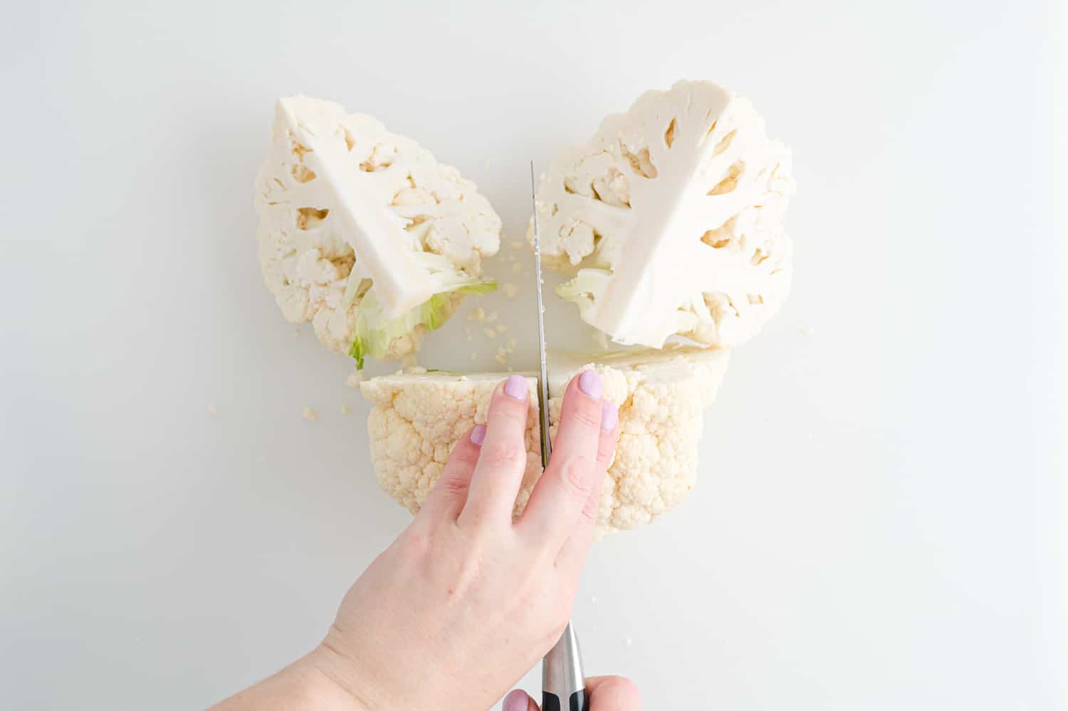 Cauliflower, being cut into quarters.