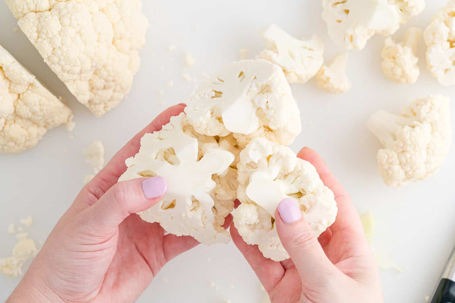 Large piece of cauliflower being broken into smaller pieces.