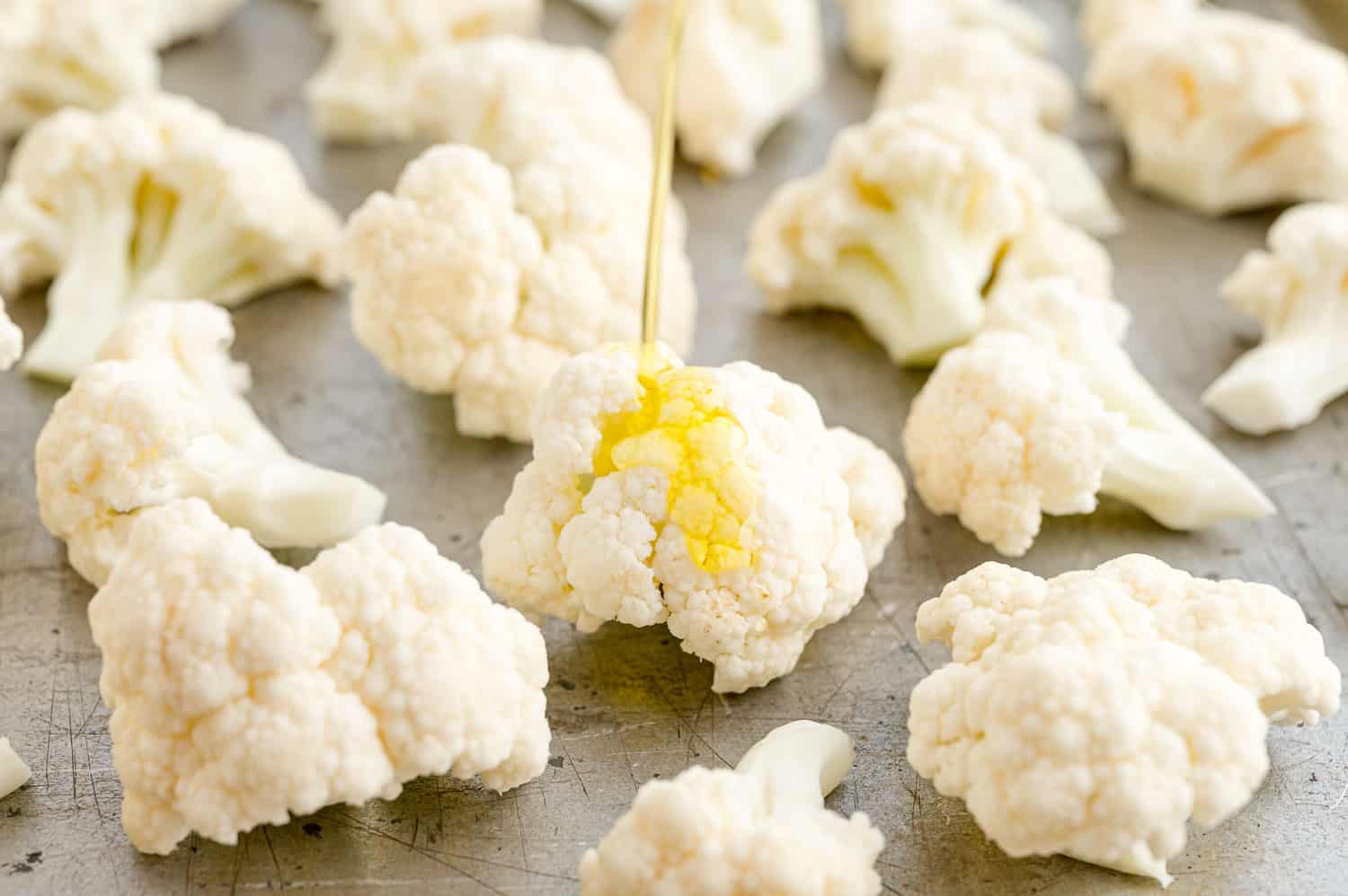 Olive oil being poured on cauliflower.