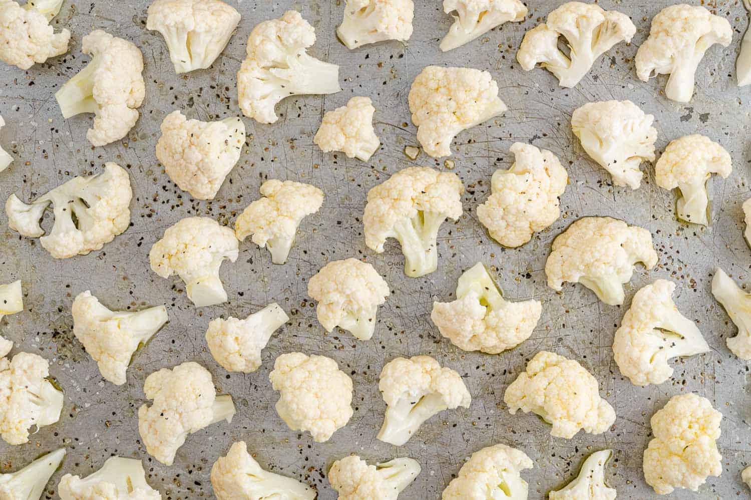 Uncooked cauliflower on a baking sheet.