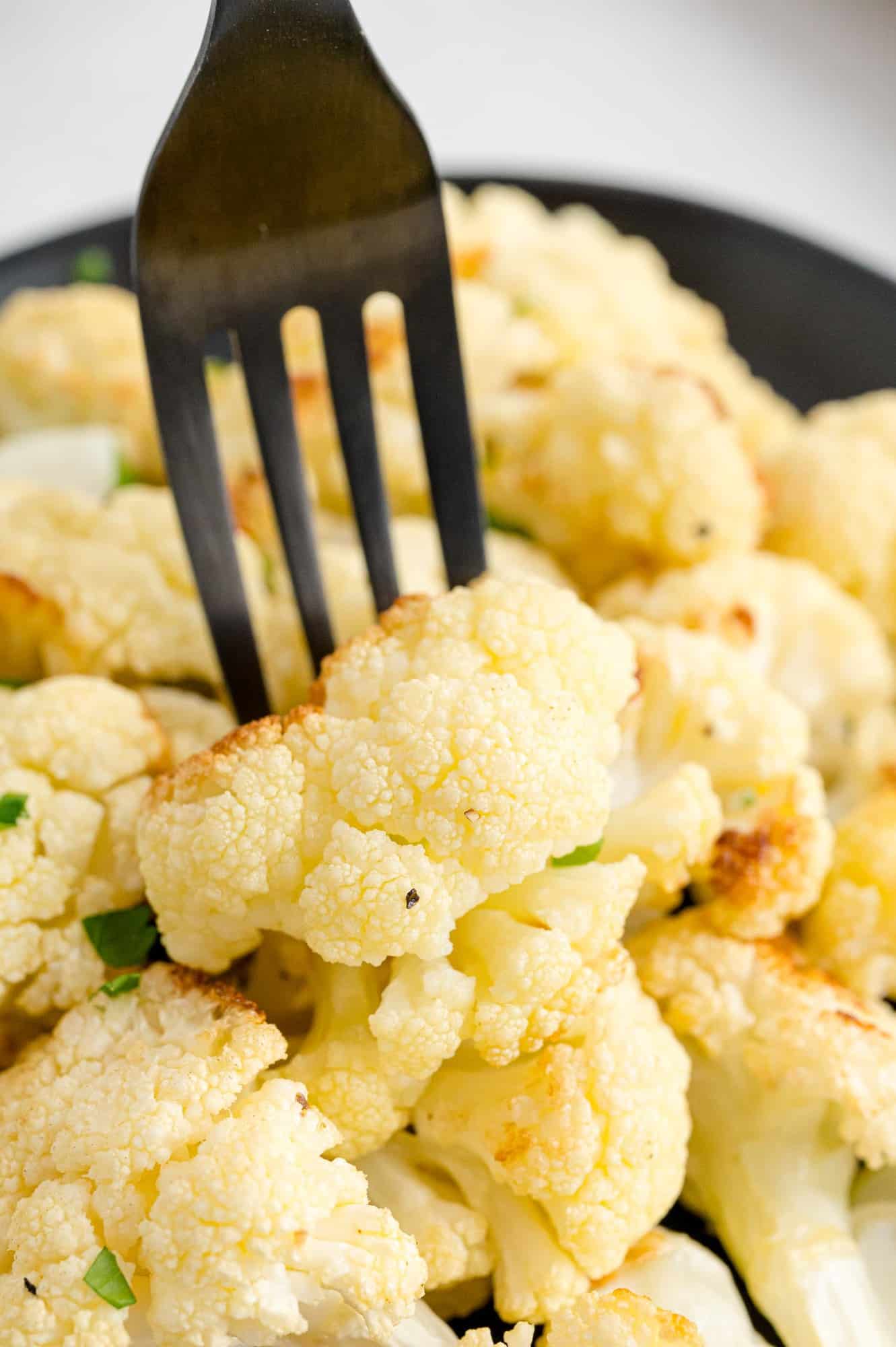 Roasted cauliflower on a black fork.