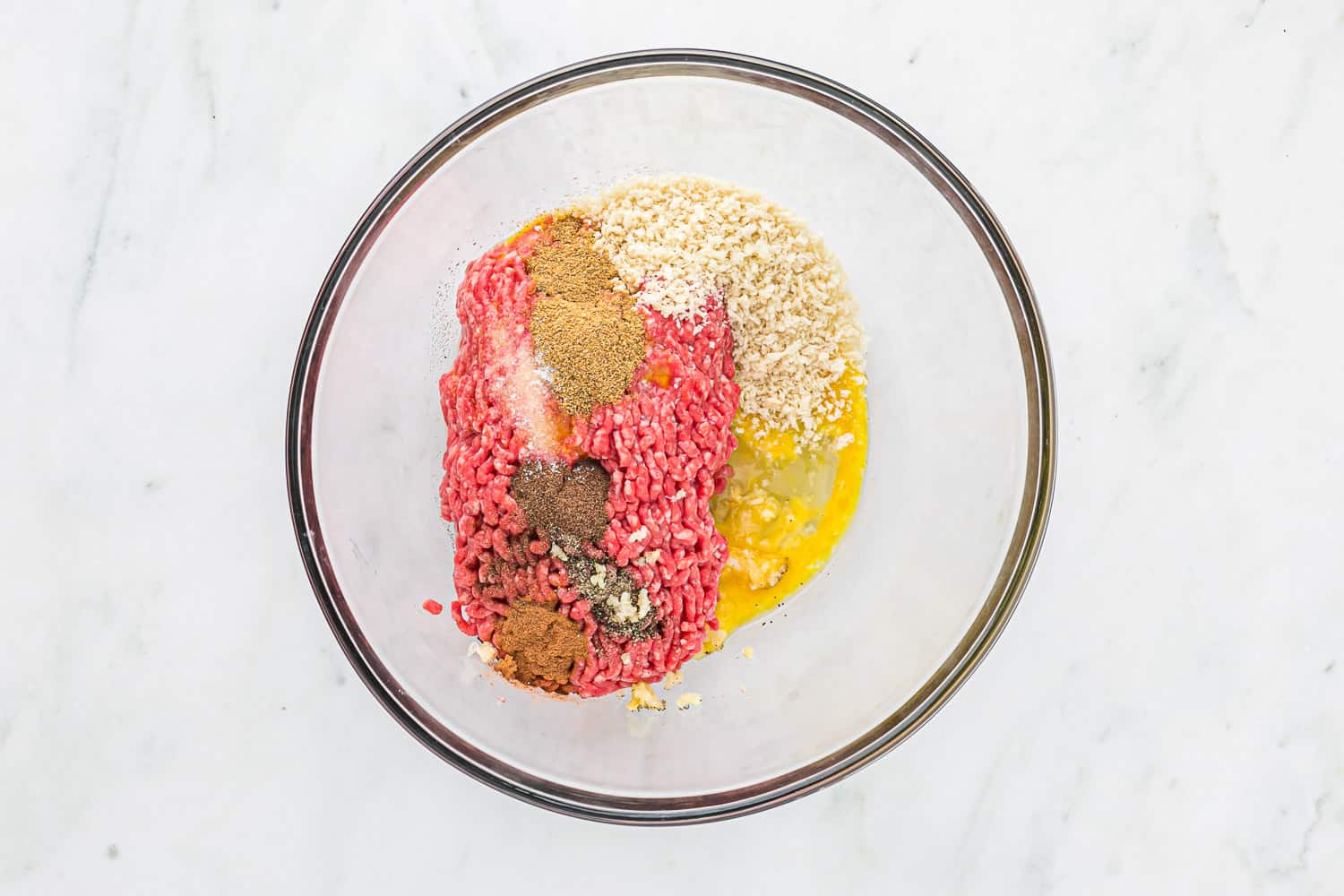 Meatball ingredients in a glass mixing bowl.