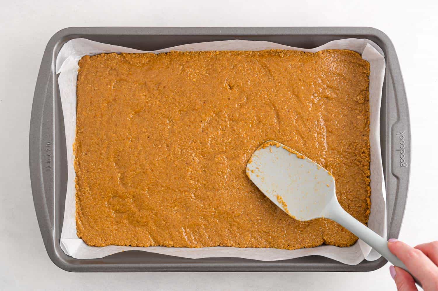 Peanut butter layer being pressed into pan.