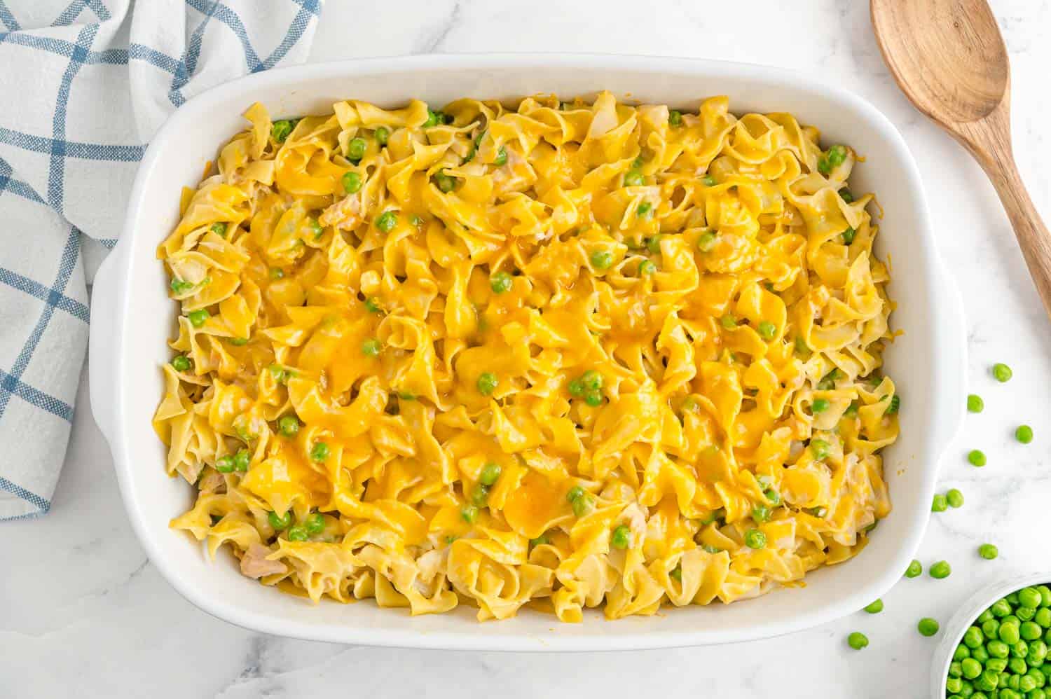 Baked casserole with tuna and peas in a white baking dish.