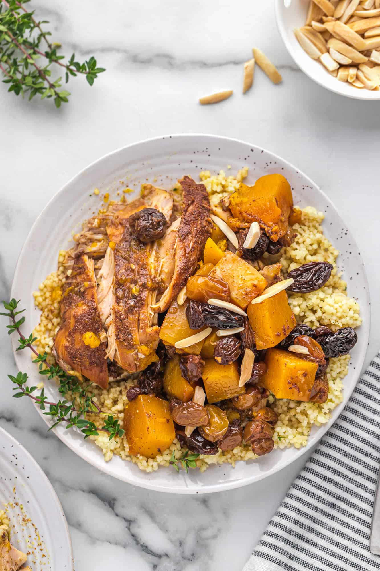 Overhead view of round white plate with moroccan chicken thighs and squash.