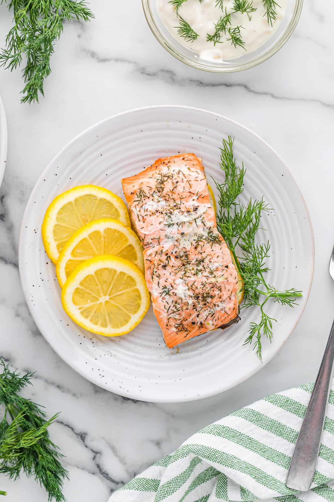 Overhead view of plated salmon with lemon slices and dill sprigs.