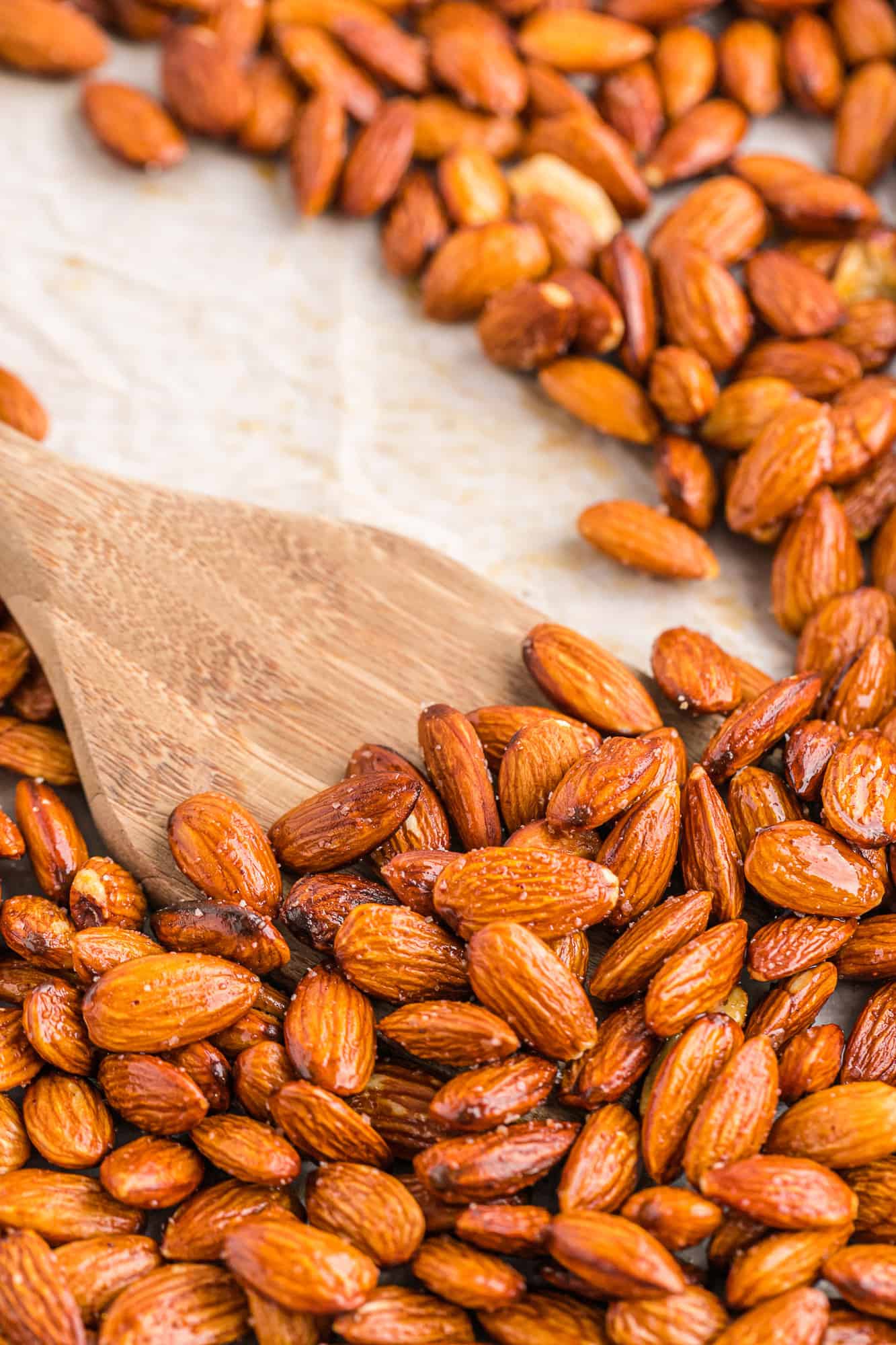 Almonds on a tray with a wooden spatula.