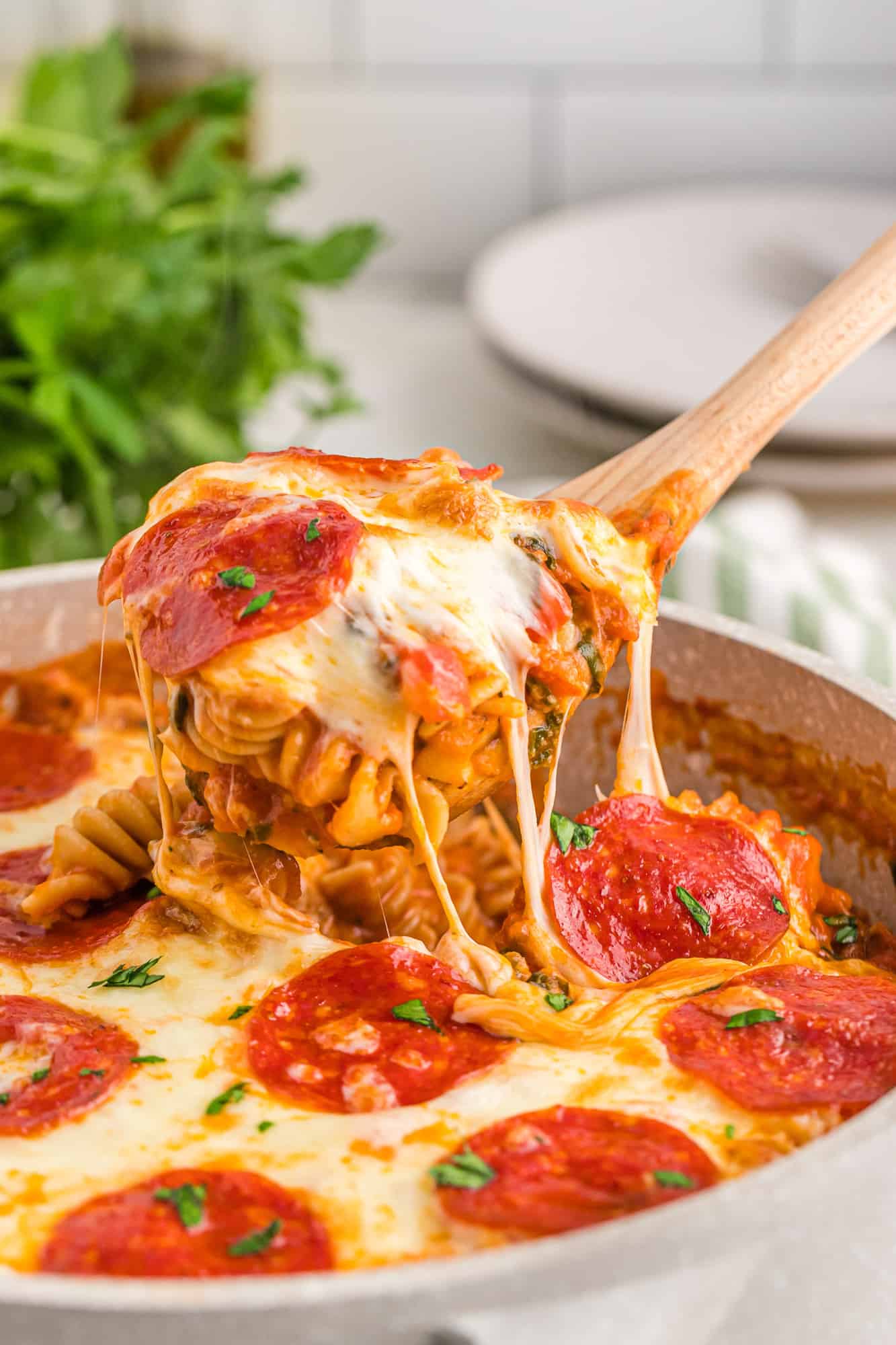 Pizza pasta being scooped out of a baking dish.