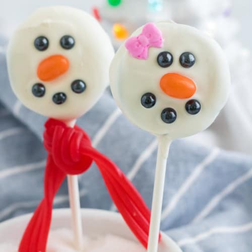 Two oreo snowmen pops, one decorated to look like a girl.