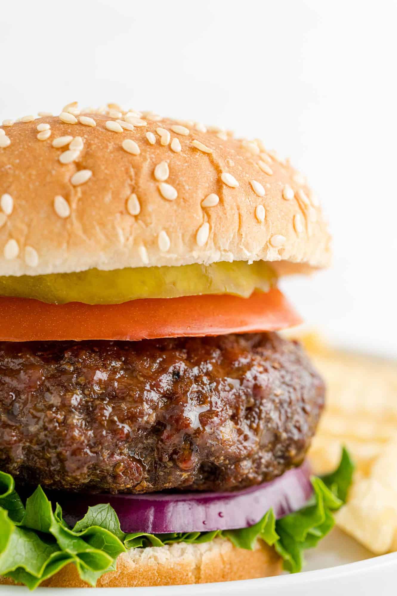 Close up of thick, juicy air fryer hamburger on a sesame seed bun.