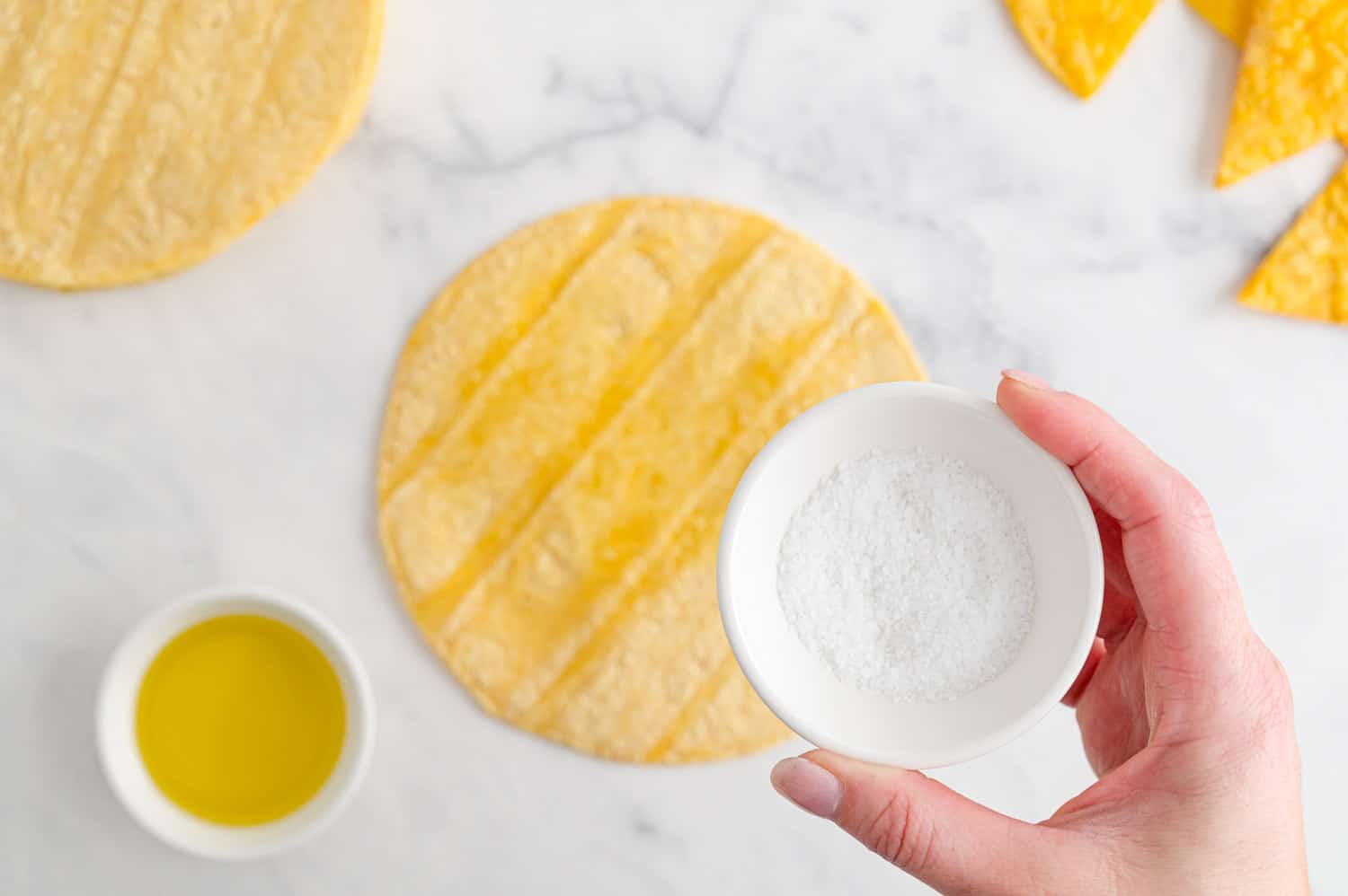 Salt being sprinkled on a corn tortilla.