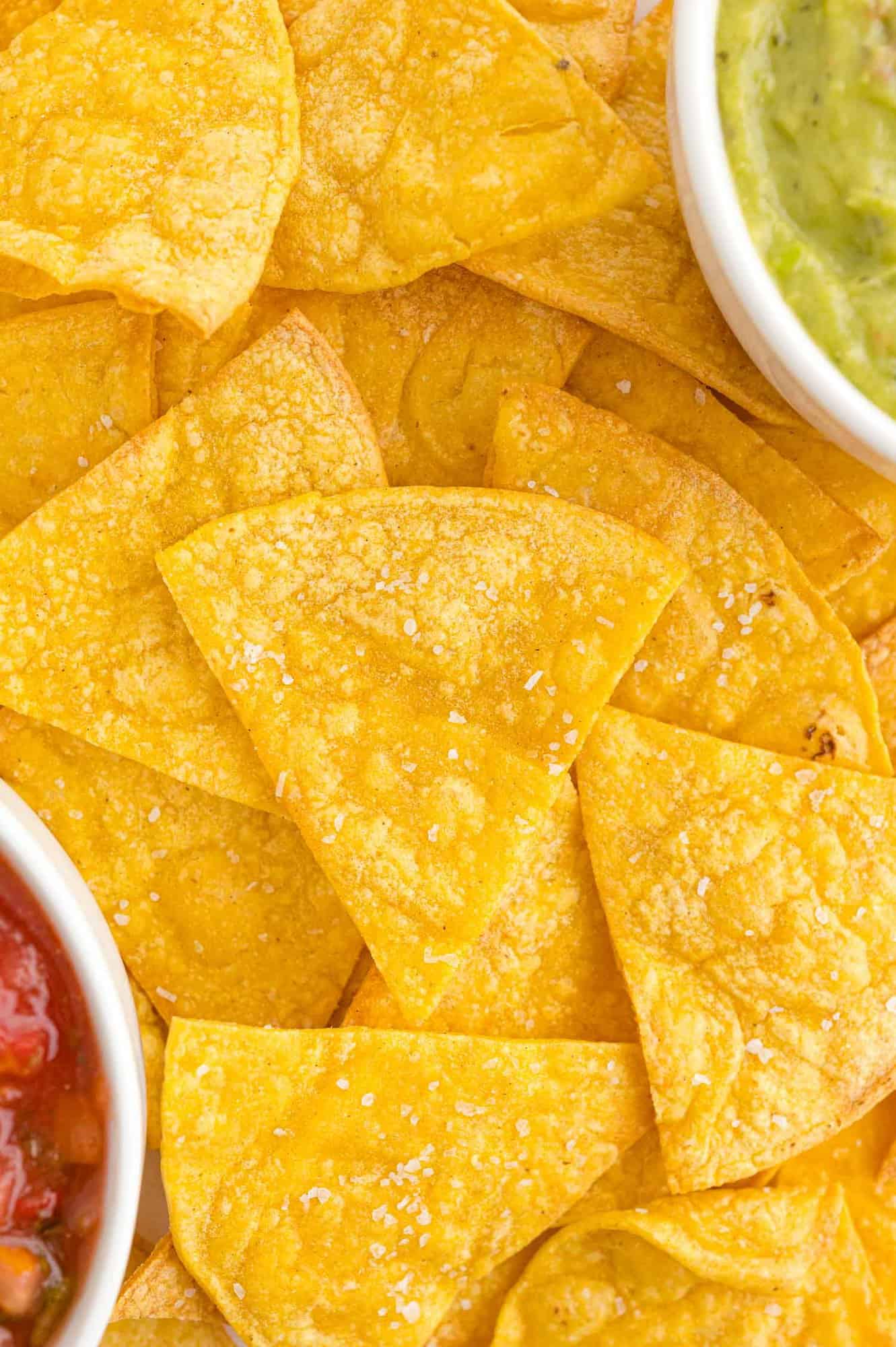 Layers of tortilla chips, guacamole and salsa partially visible.