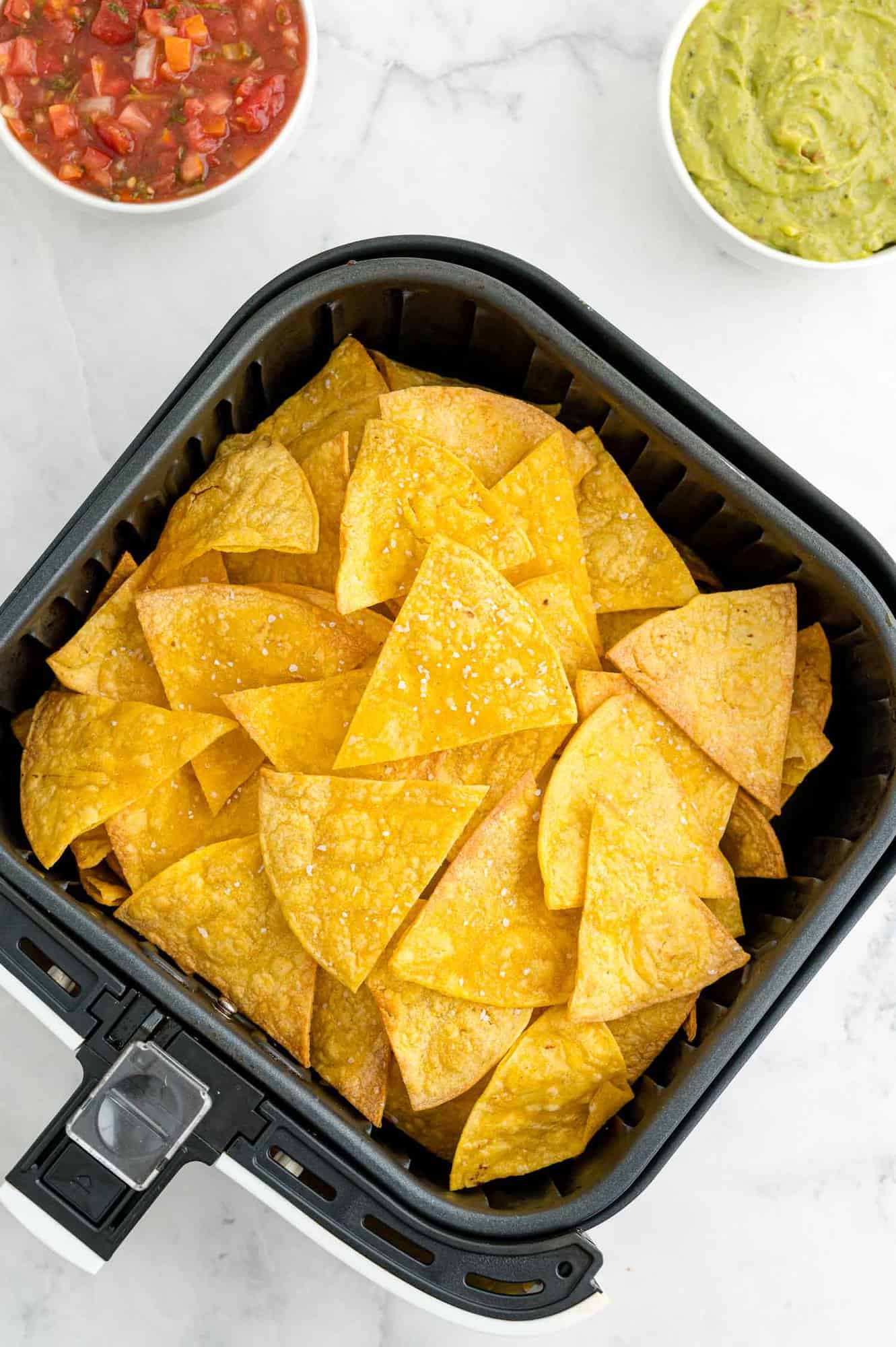 Corn tortilla chips in an air fryer basket.