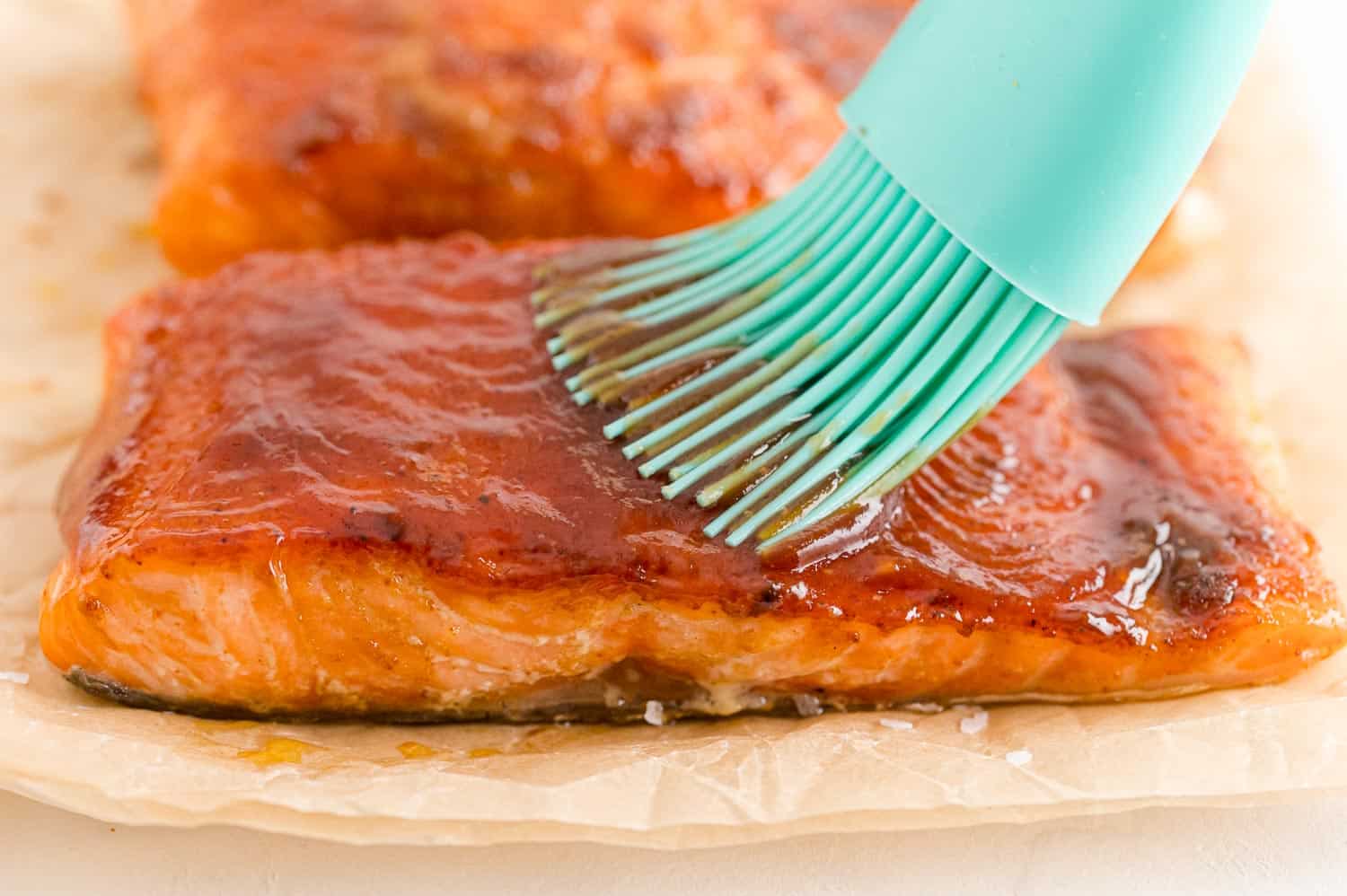 Barbecue sauce being brushed onto salmon.