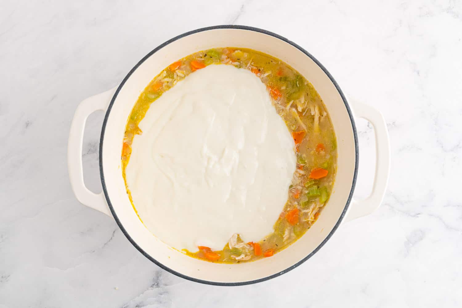 White sauce being added to soup.