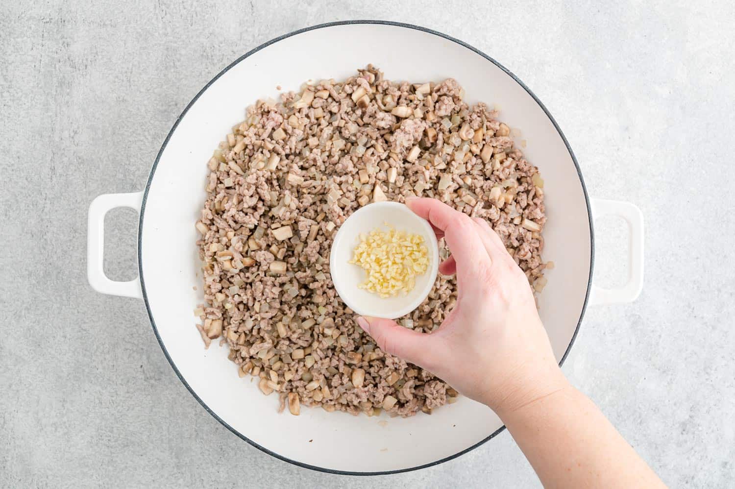 Garlic and ginger being added to ground meat.