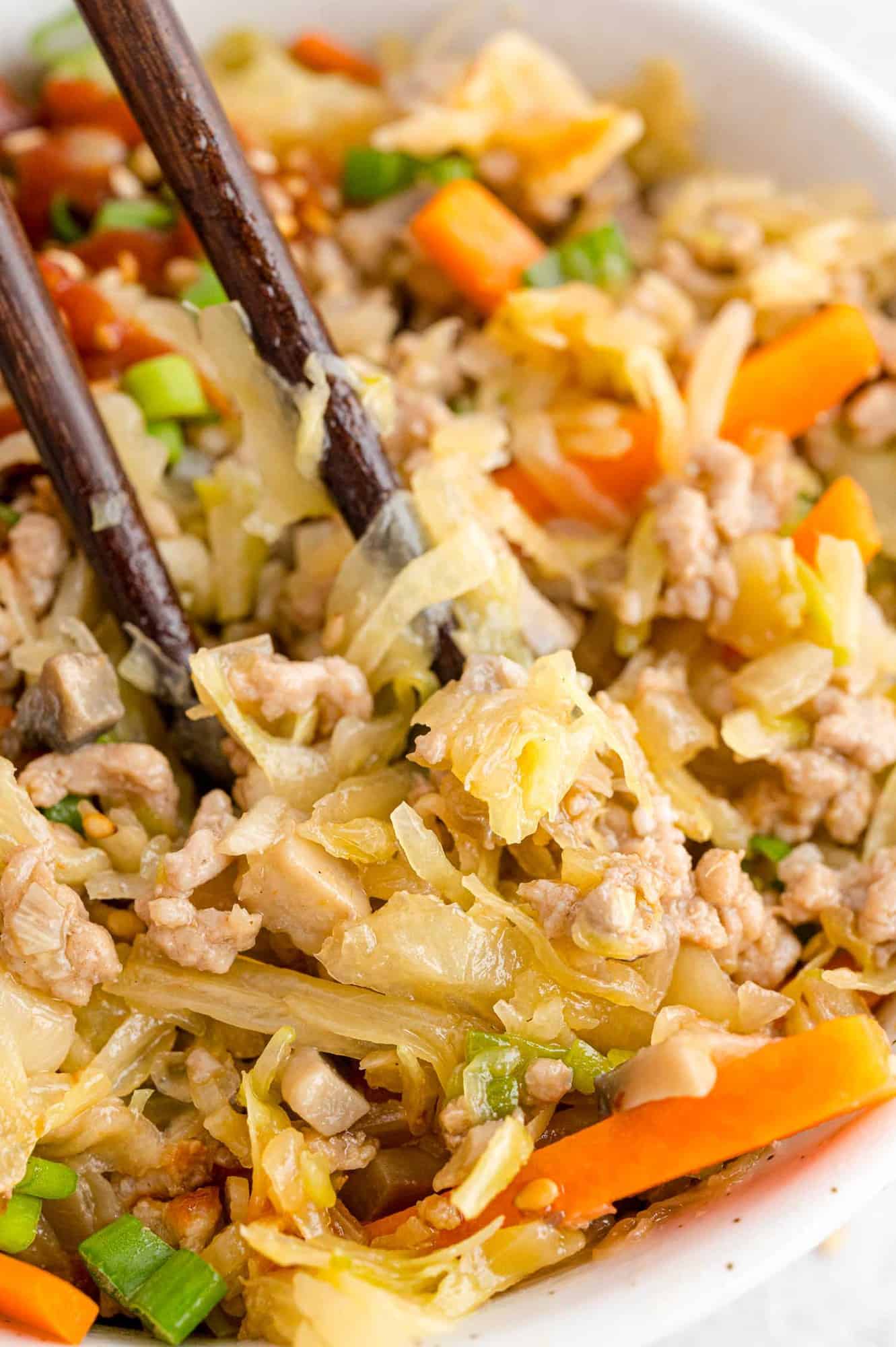 Close up of egg roll mixture between chopsticks.