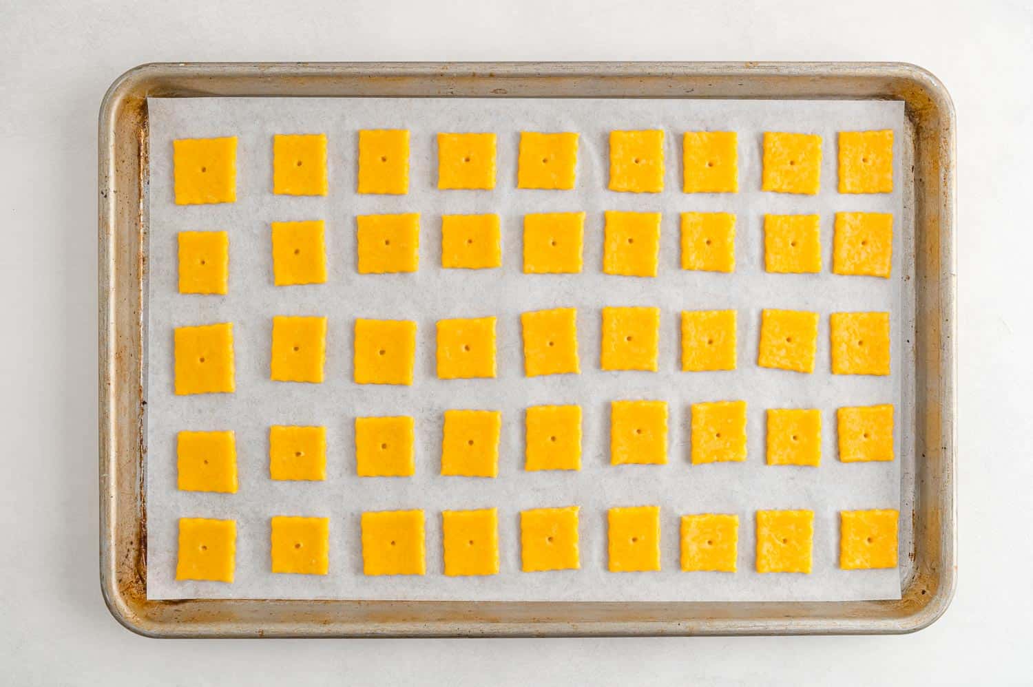 Unbaked cheez-its on a baking sheet.