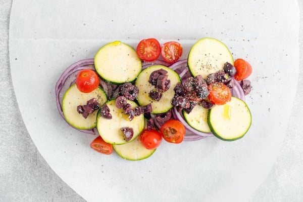 Chopped vegetables arranged over a parchment paper oval.