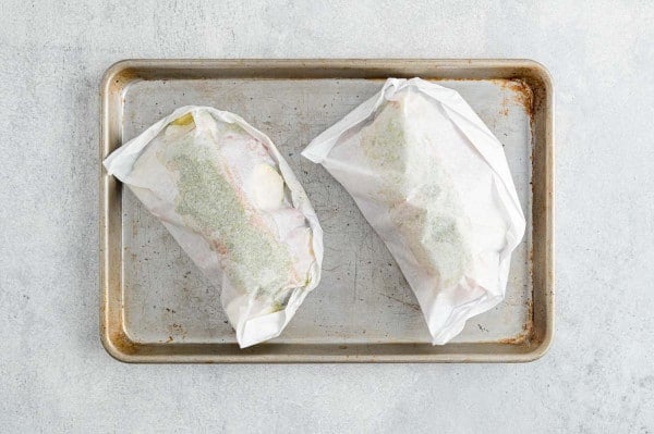 Pesto salmon in packets on a baking sheet.